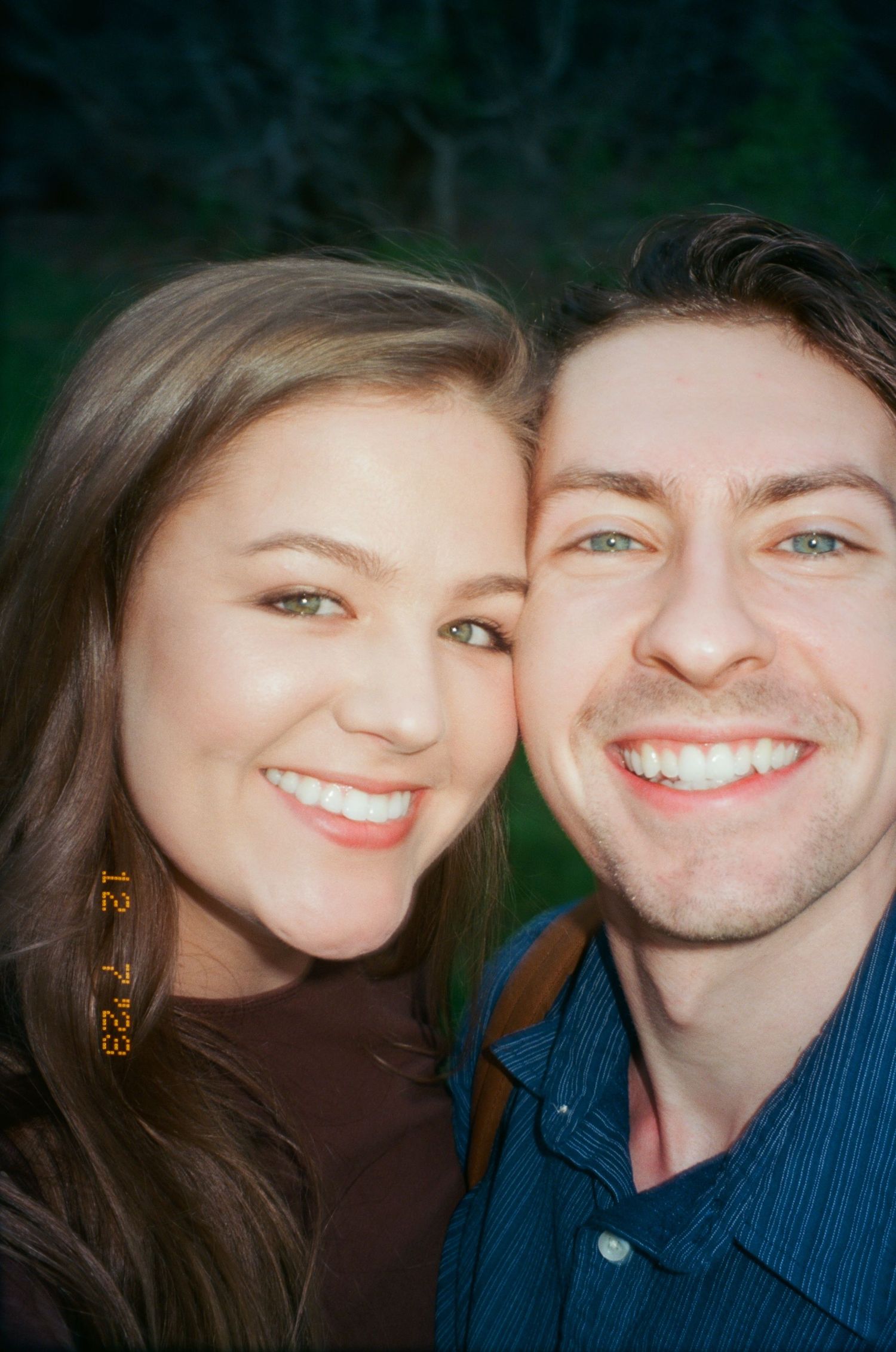 Happy young couple smiling closely together in a vintage film photo dated 12-23.