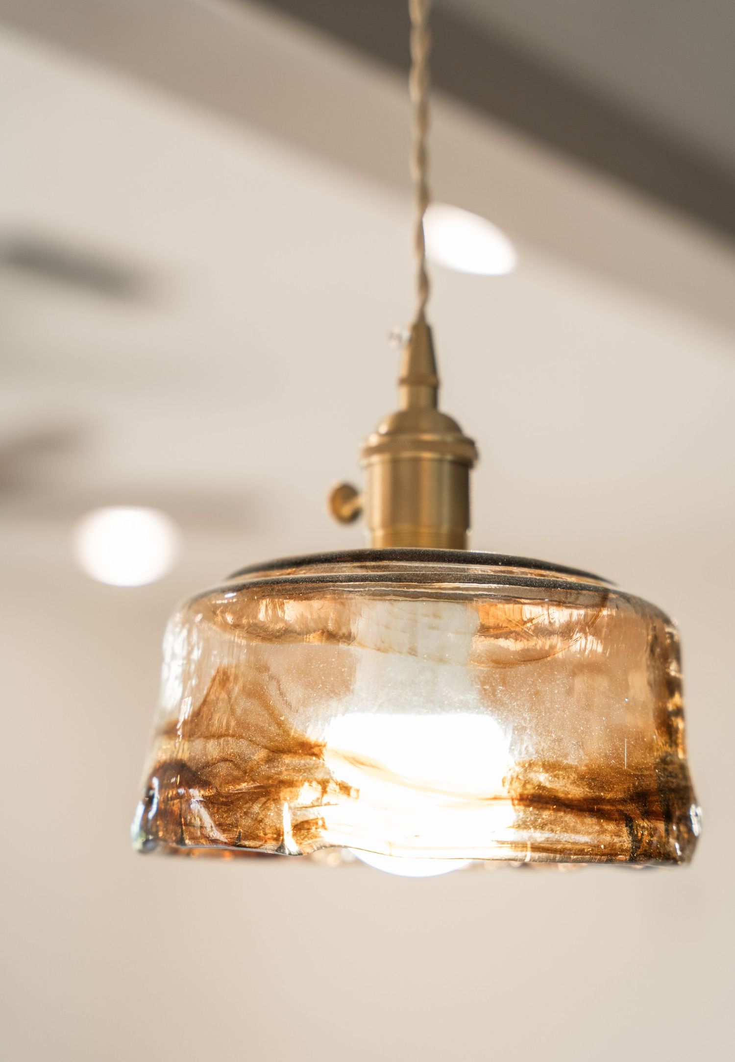 Amber glass pendant light with brass fitting illuminates a bright modern interior space.