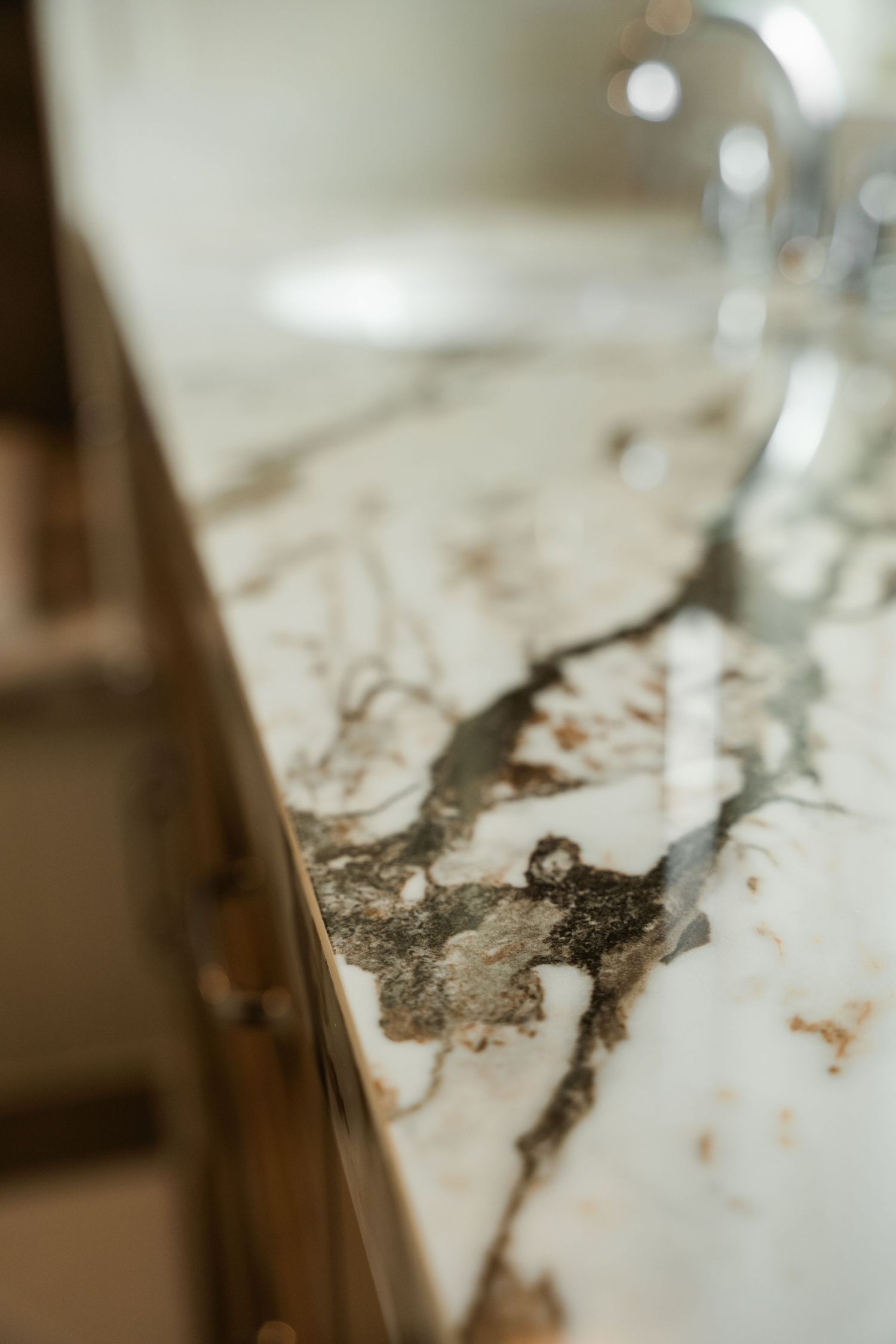 Close-up detail of dramatic white marble countertop with bold dark veining and warm wood cabinetry below.