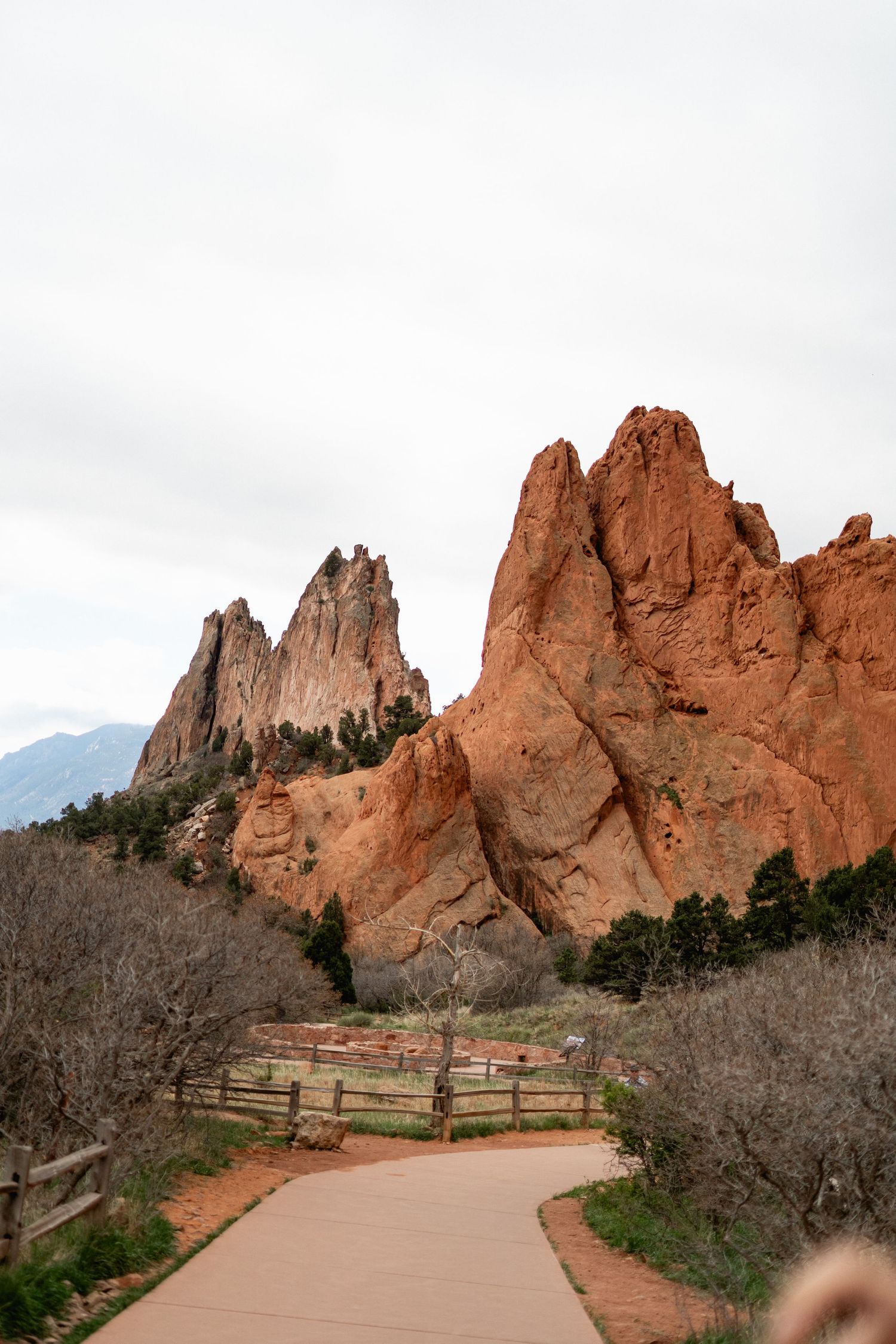 Dramatic red rock formations tower over a winding paved path at Garden of the Gods, Colorado Springs.
