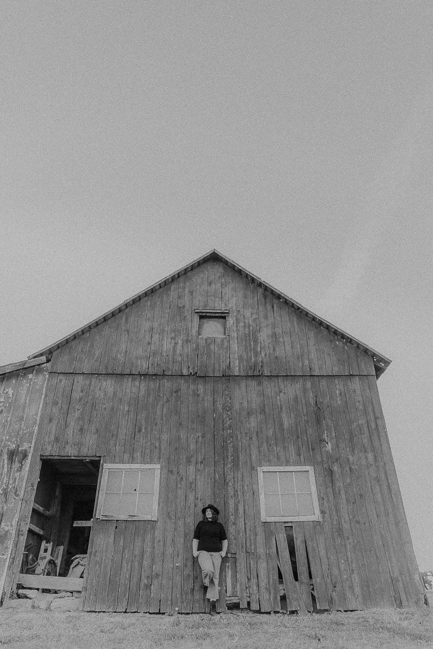 A series of black and white photographs showing different angles of a weathered wooden barn with broken windows and doors.