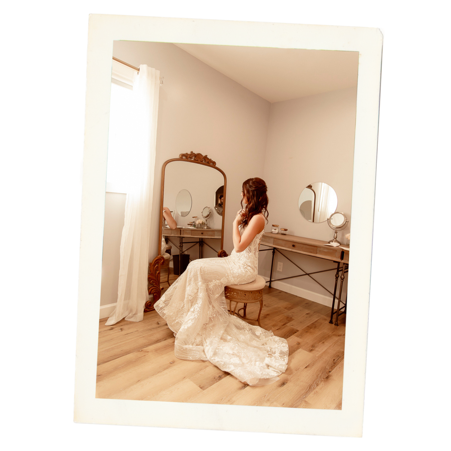 A bride in a flowing white wedding gown poses gracefully in a minimalist room with natural lighting.