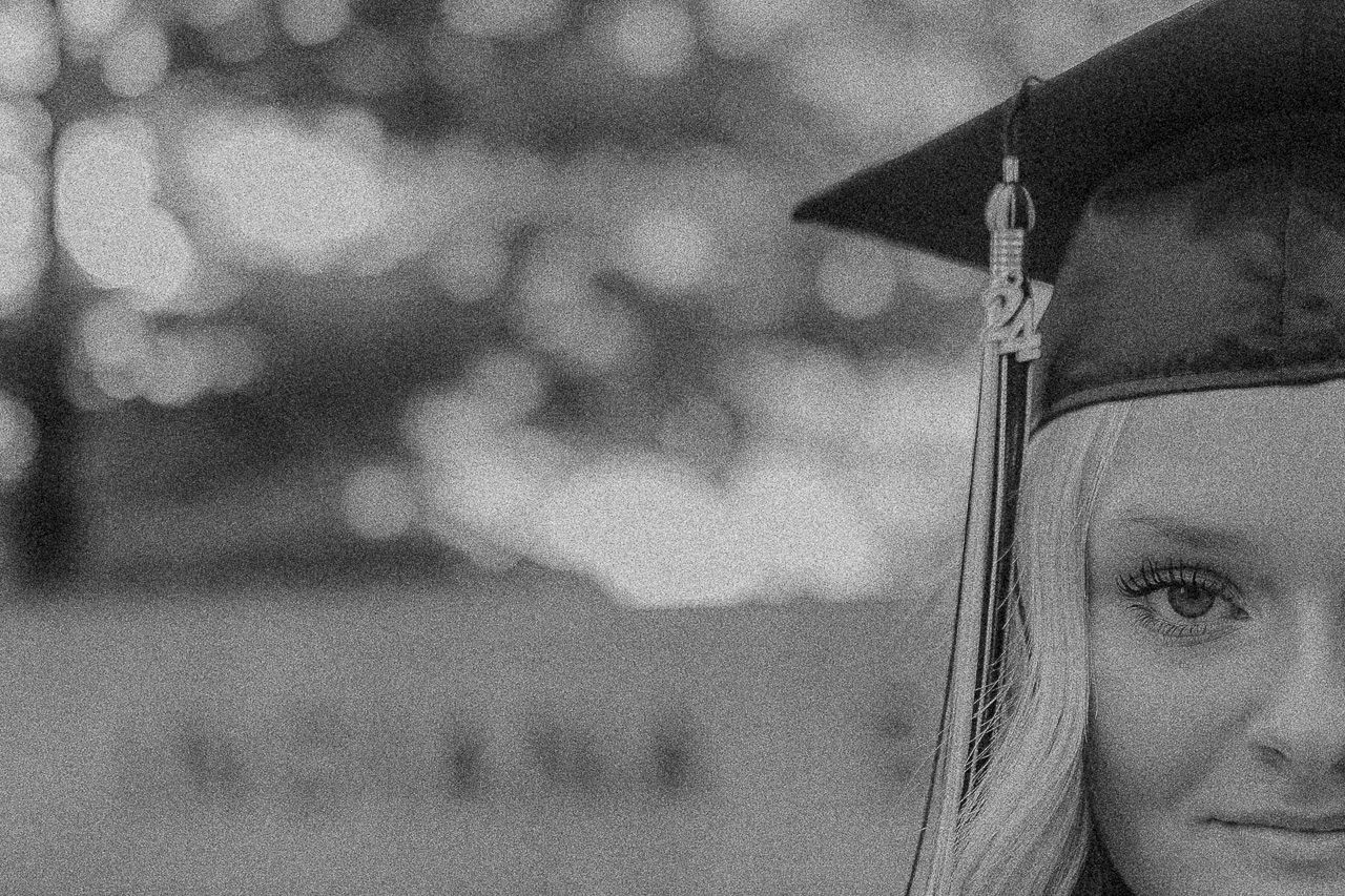 A black and white graduation photo montage with graduates wearing caps and gowns against a blurred background.