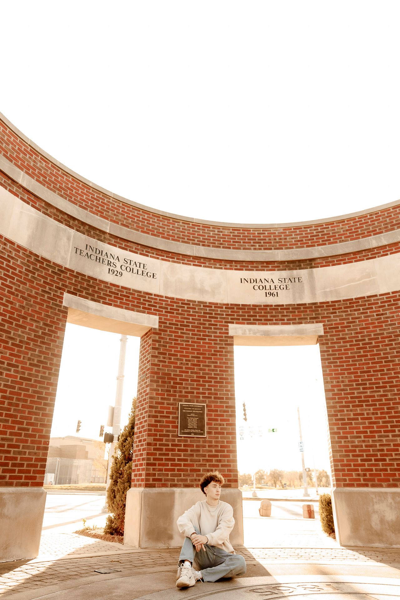 Curved brick wall interior with arched windows casting dramatic shadows in a minimalist architectural space.
