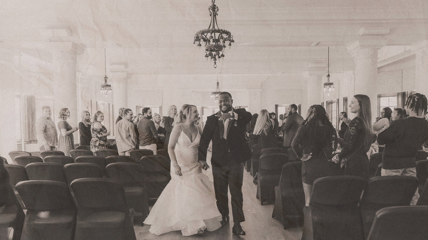 Black and white photo of a bride and groom walking down the aisle after their wedding ceremony.