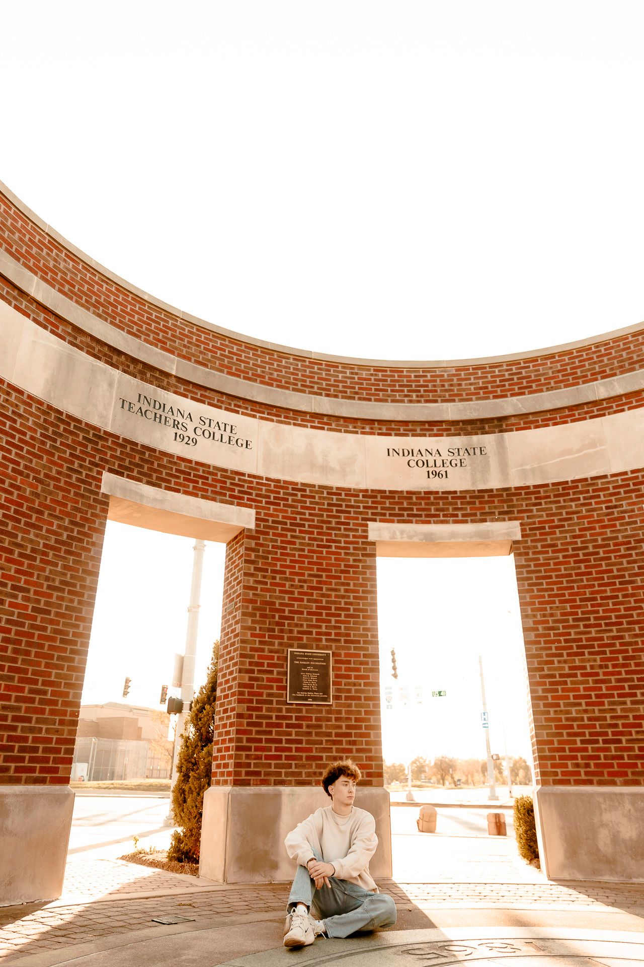 Student sitting at the Indiana State Teachers College brick monument on Indiana State University campus.