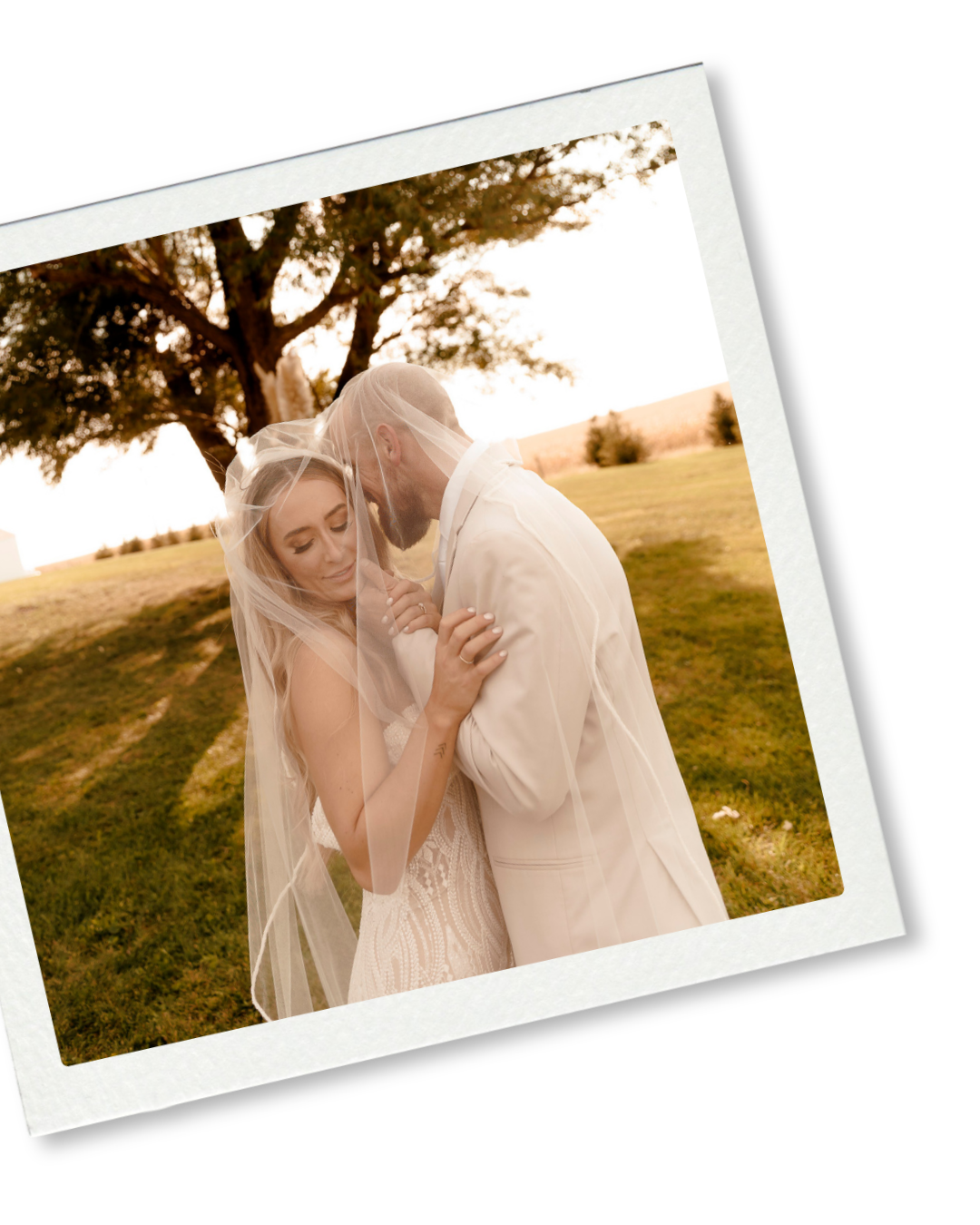 A bride and groom share an intimate moment under a veil outdoors during golden hour at their wedding.