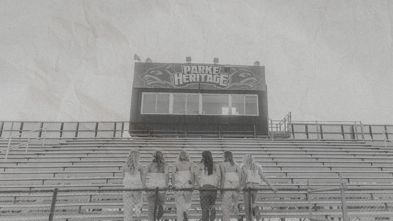 Black and white photograph of empty bleachers and stadium seating at an outdoor sports venue.