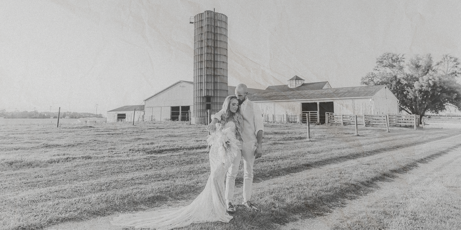 A black and white panoramic view of a rural farmhouse and barn buildings set against rolling countryside fields.