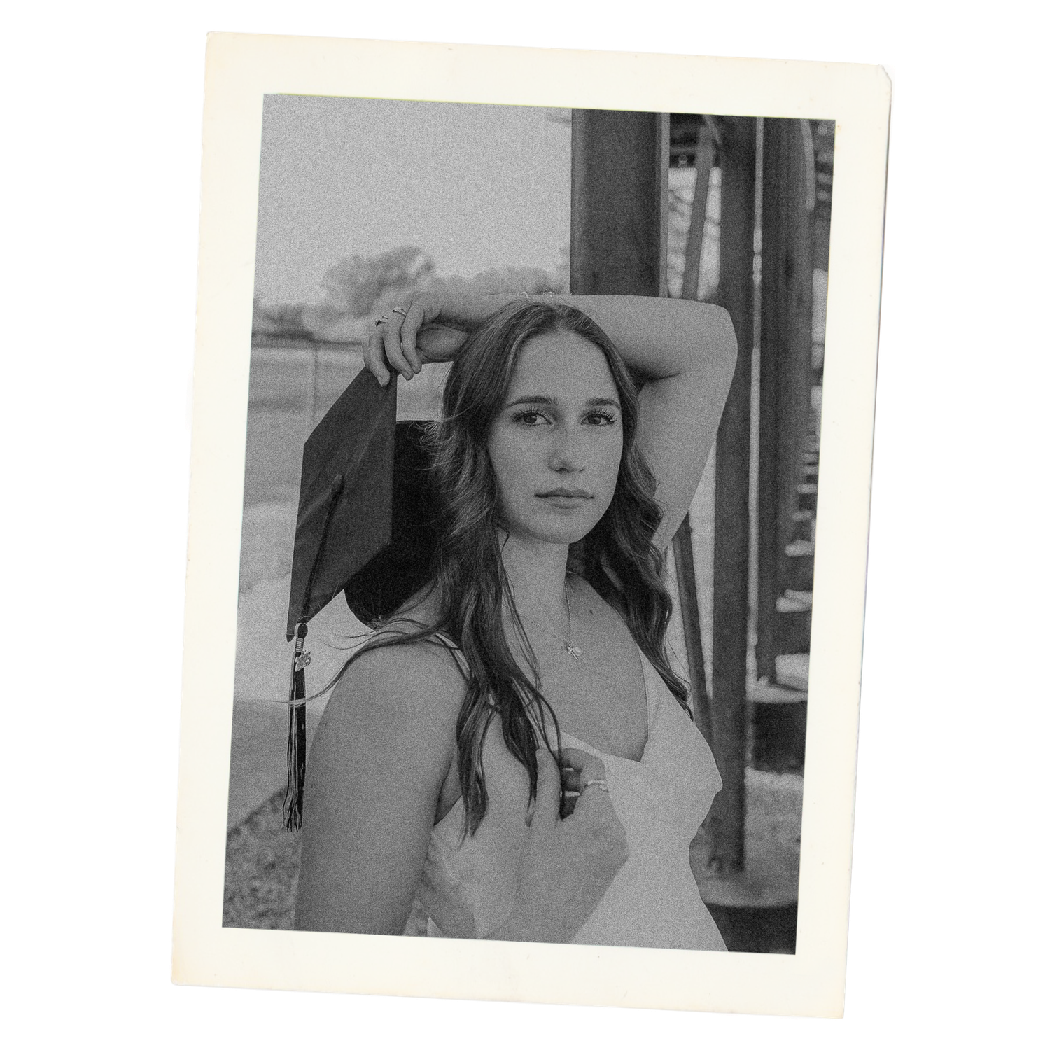 Black and white portrait photograph showing a young person with long dark hair wearing a white top outdoors.