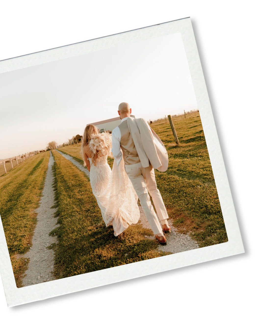 Bride and groom walking hand in hand down a scenic countryside path on their wedding day.