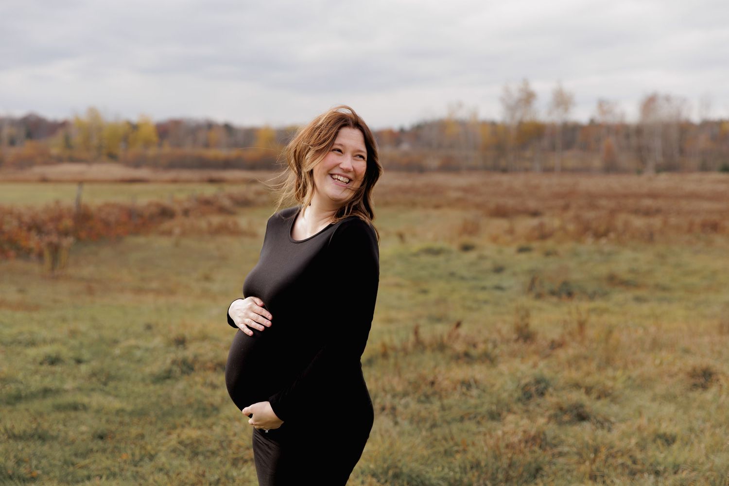 Maternity photo shoot in a rustic autumn field with warm golden light at sunset.