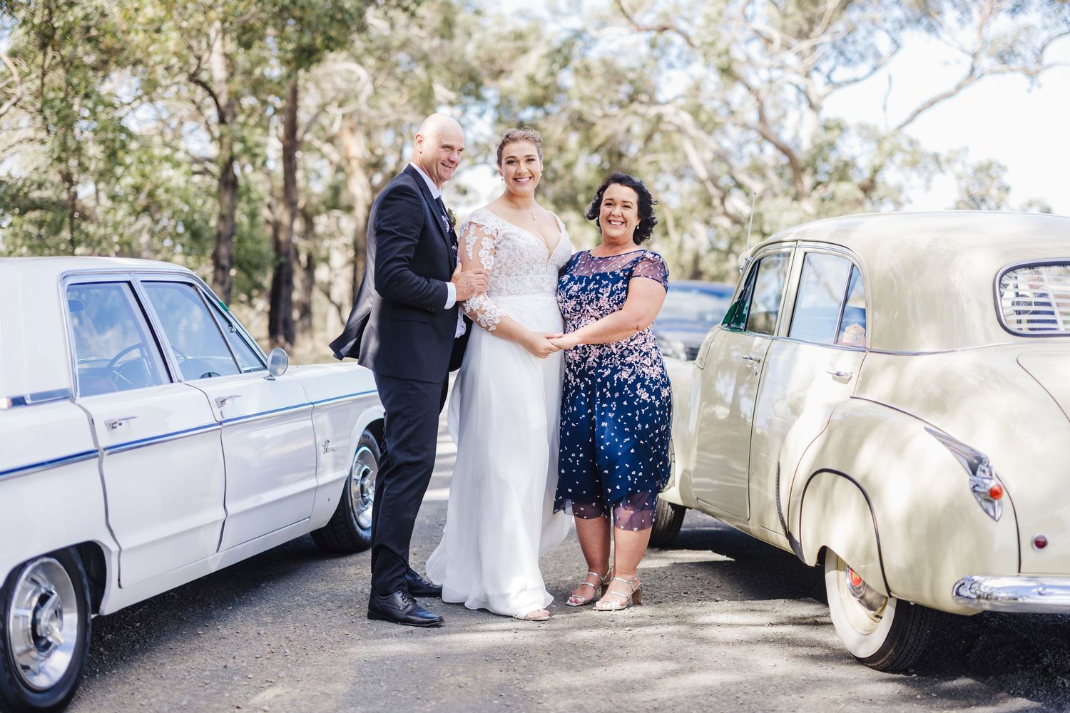 Classic vintage cars line up outside during an elegant outdoor wedding celebration.