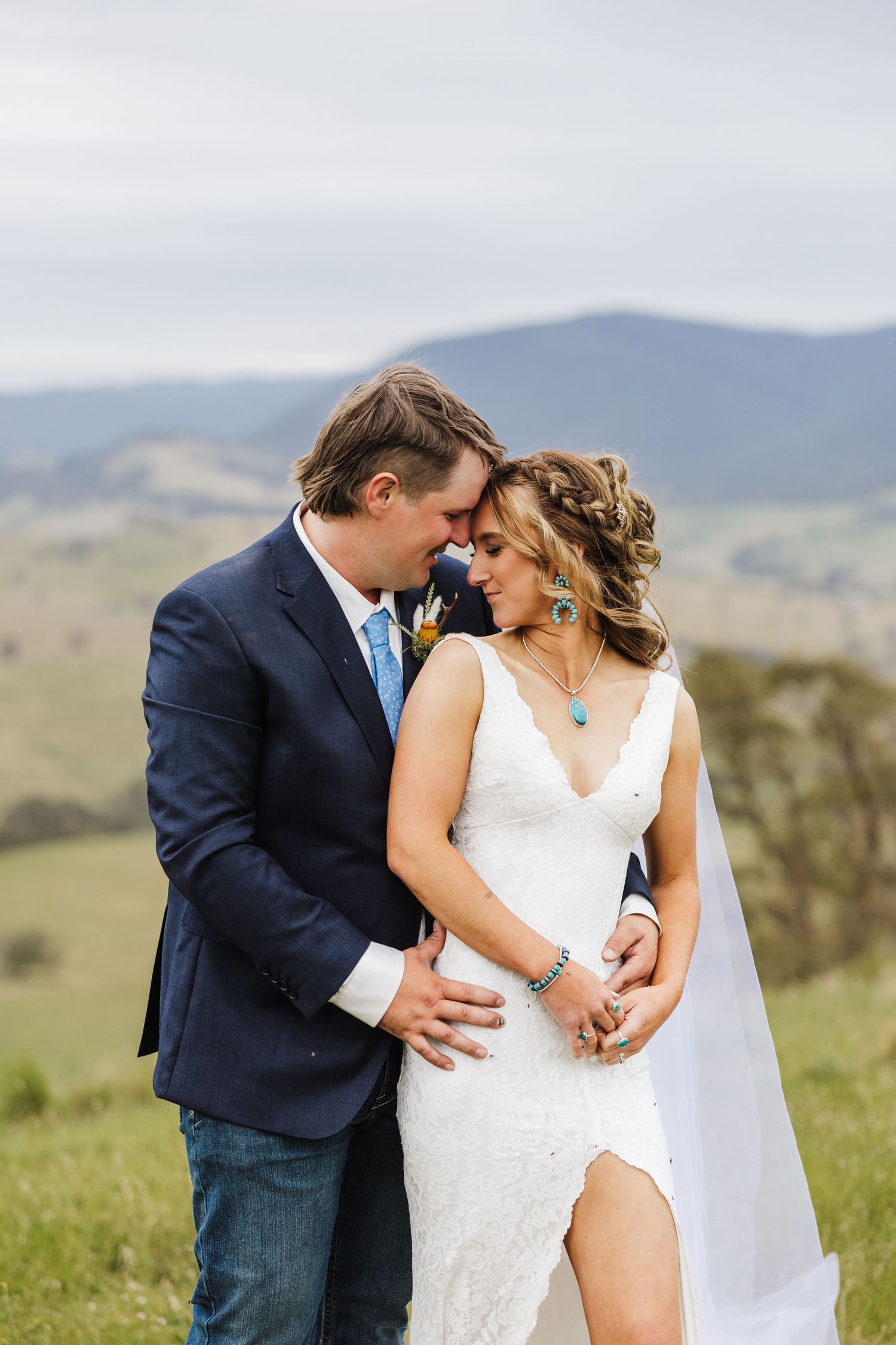 A romantic wedding photo series showing a couple embracing in a beautiful mountain meadow setting.