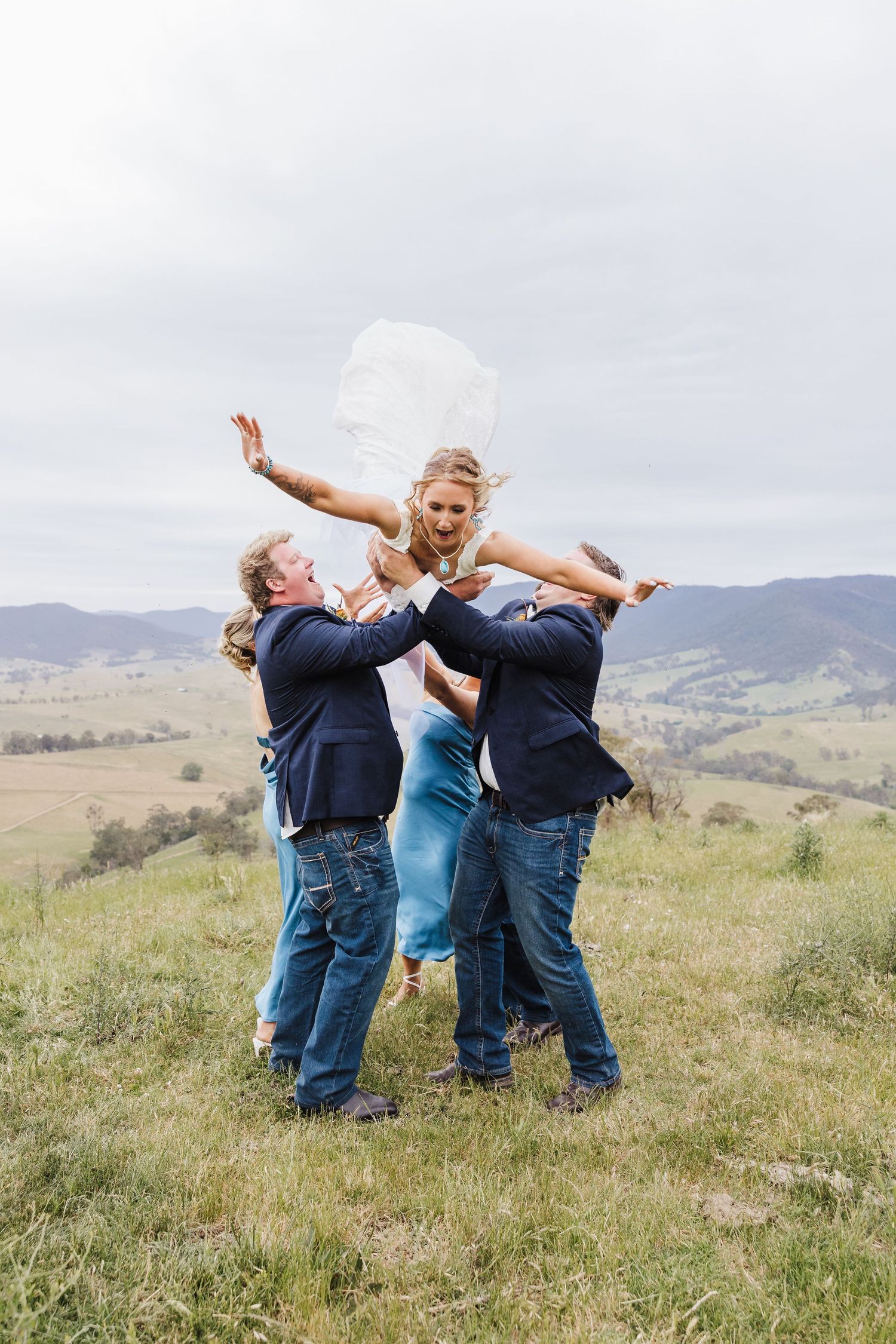 Joyful celebration on a grassy hillside with mountains in the background and blue sky overhead.