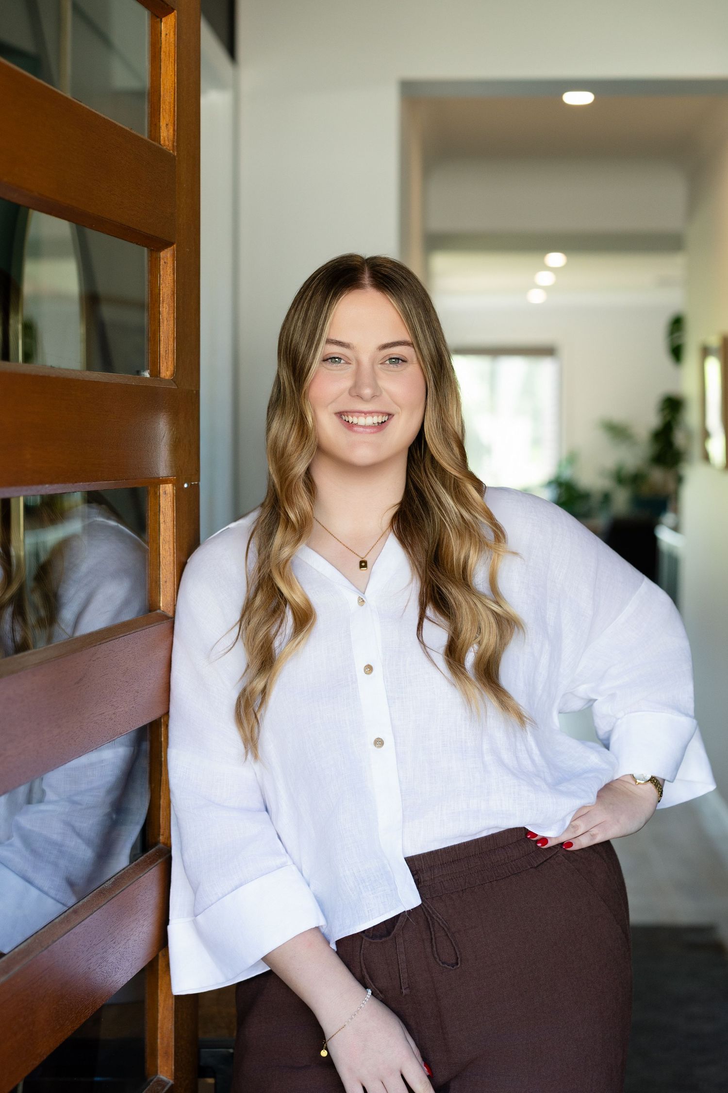 A series of photos showing someone in a white button-up shirt and brown dress sitting on a bench in a bright room.