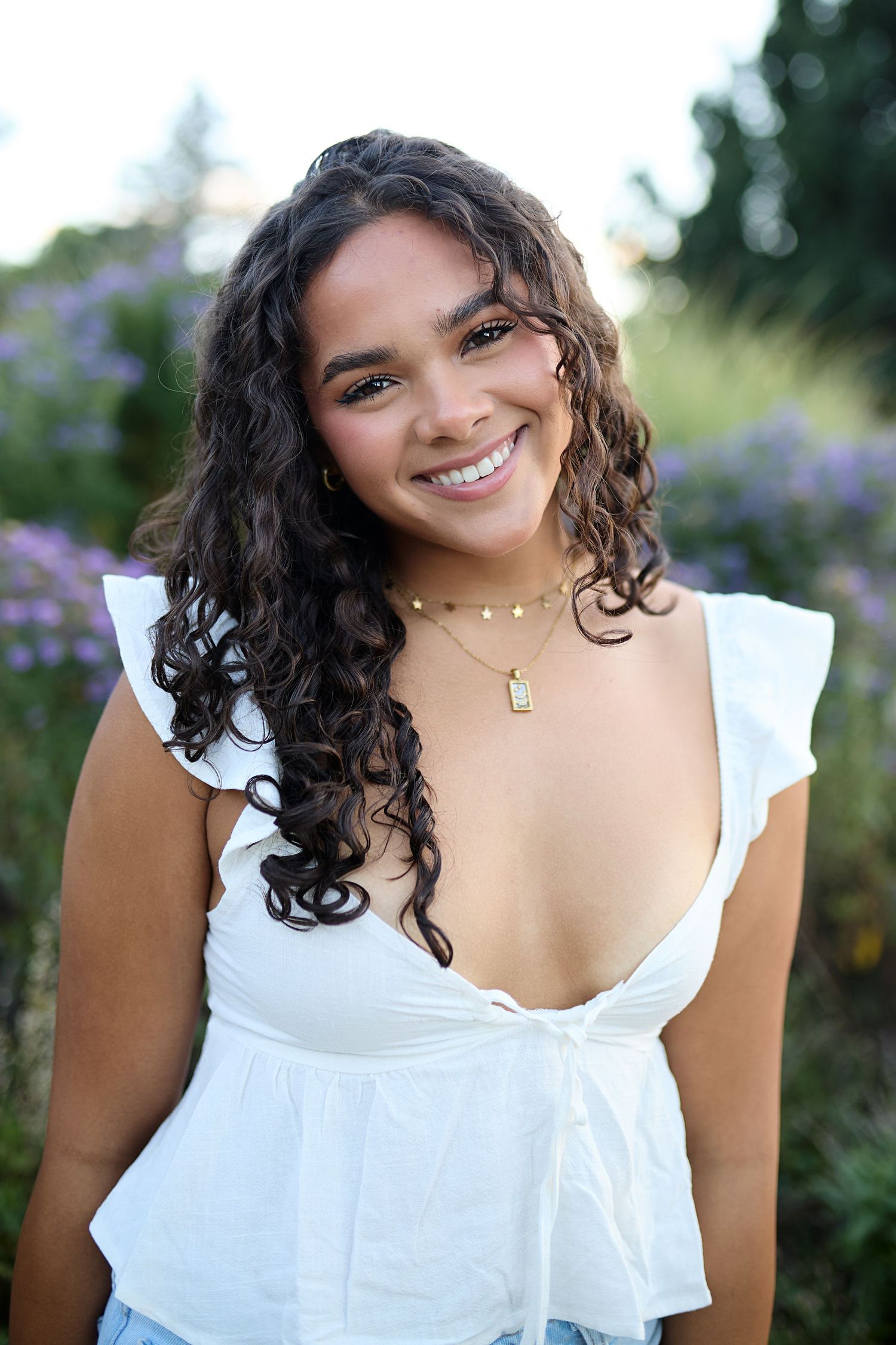 A person in a white ruffled top poses outdoors against a blurred floral background in a series of candid shots.