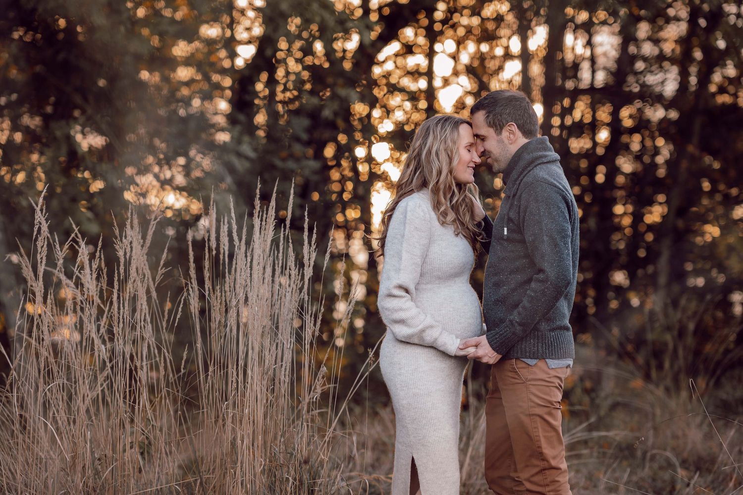 Paar steht Stirn an Stirn und genießt einen ruhigen Moment bei einer Babybauchfotografie outdoor in Stockerau