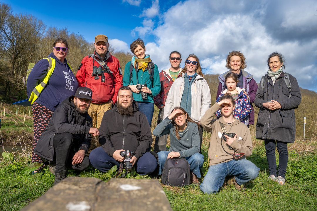 Group of searchers working in teams outdoors during a bright sunny day with cloudy skies in field terrain.