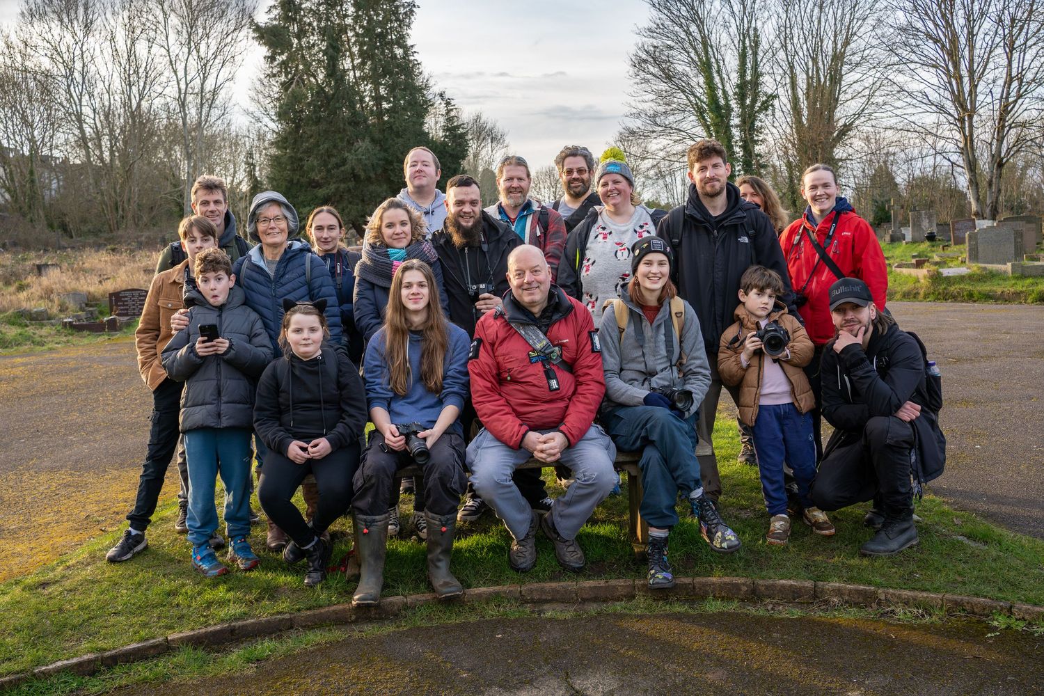 Group of people sitting together outdoors on a winter day in a park setting.