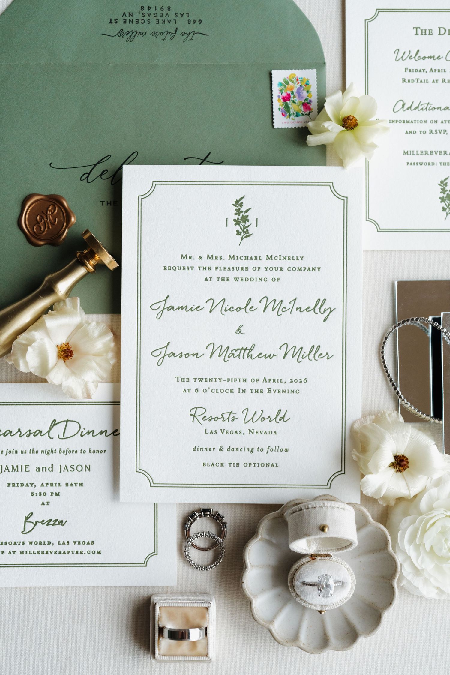 Elegant green and white wedding invitation suite with wax seal, rings, and floral accents on a sage green background.