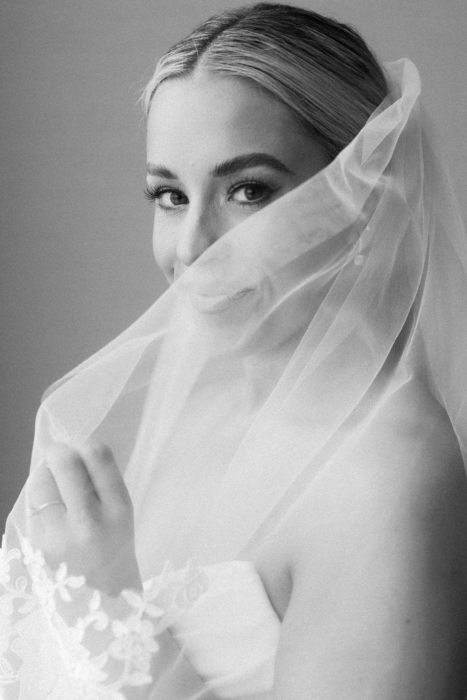 Close-up sequence of a delicate white bridal veil with lace details against a gray background.