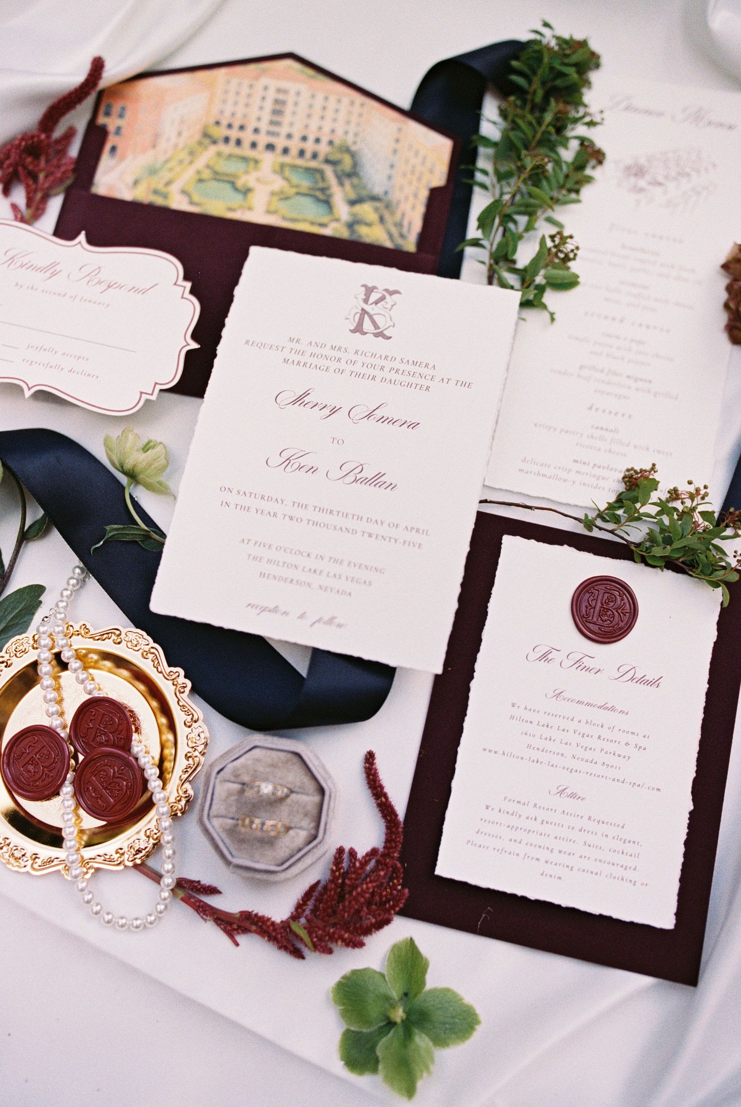 Elegant wedding invitation suite with burgundy wax seals, navy ribbon, floral details, and deckled edge cards on white background.