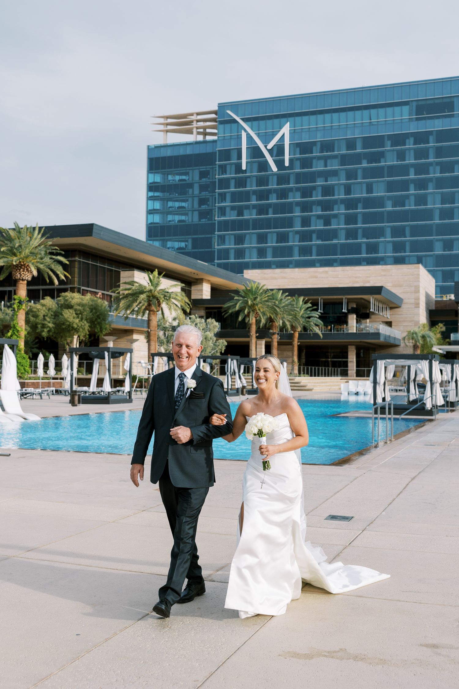 Bride and father walk poolside at M Resort Las Vegas wedding venue on a sunny day.