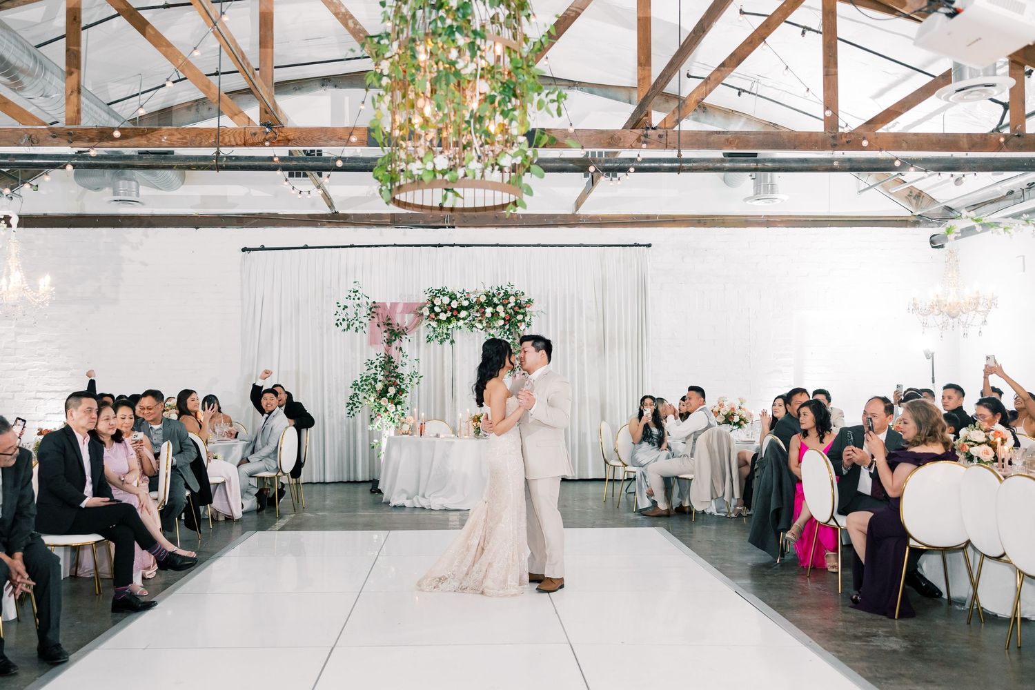 Wedding reception in a rustic venue with exposed wooden beams and white decor.