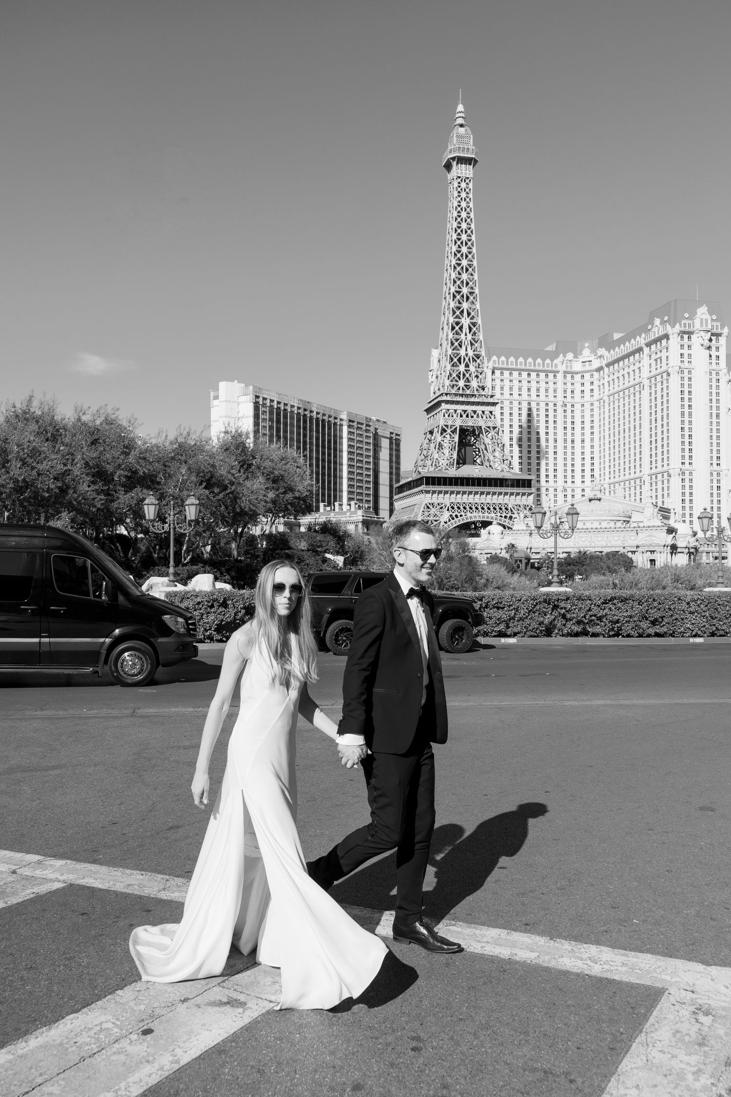 Black and white wedding photo of a couple holding hands on the Las Vegas Strip with the Paris Hotel Eiffel Tower behind them.