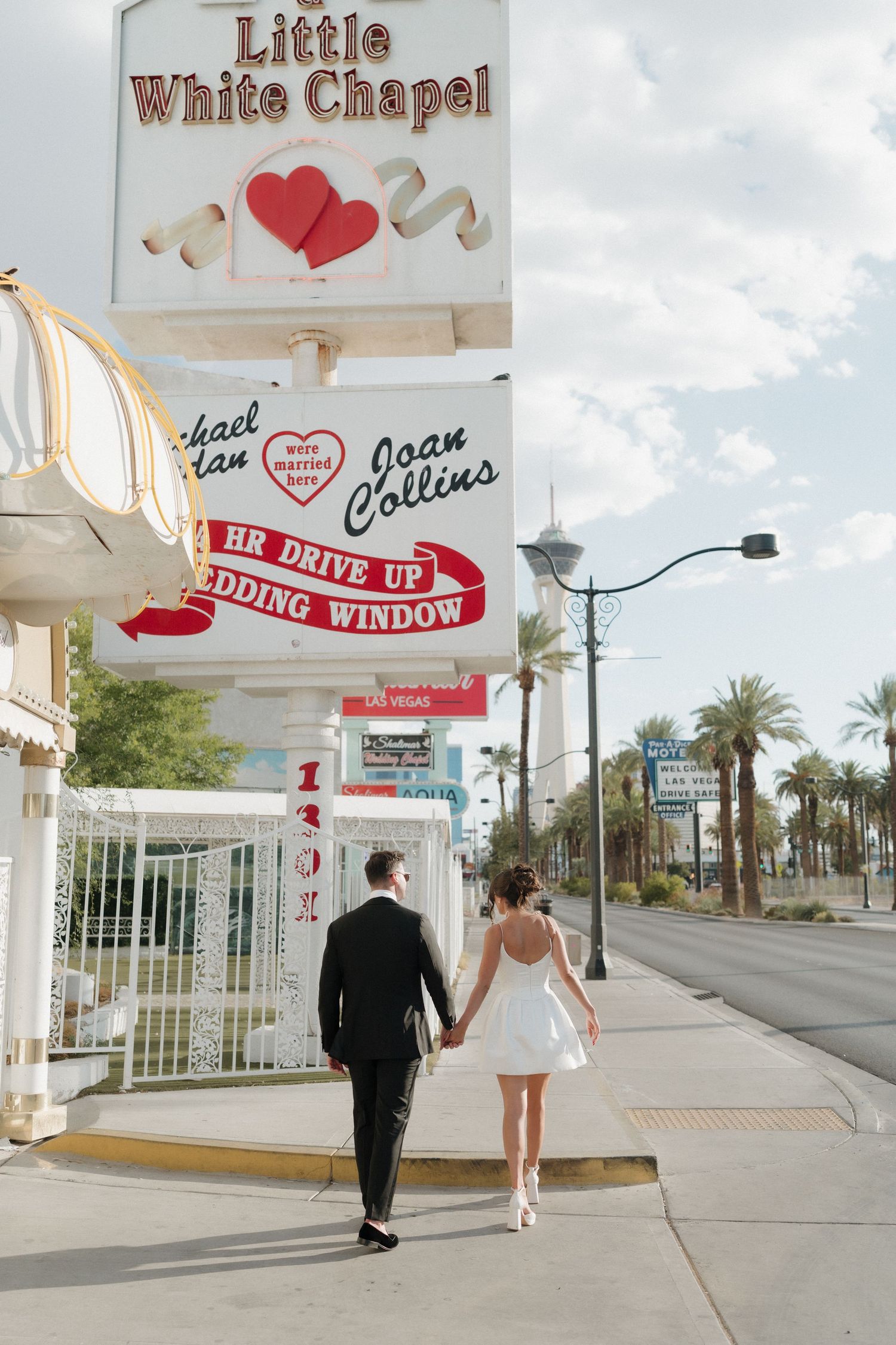 Couple in wedding attire holding hands outside the Little White Chapel in Las Vegas, Nevada.