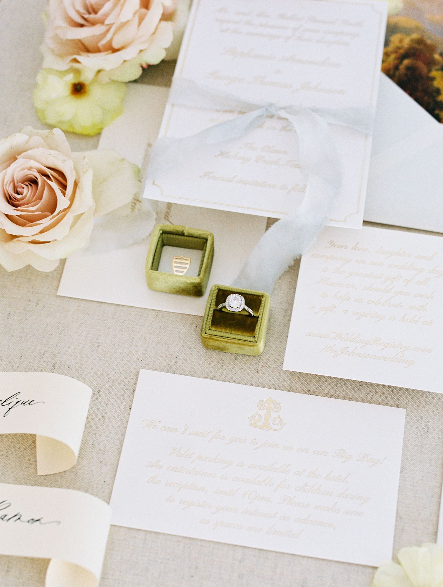 Elegant wedding stationery suite with calligraphy, blush roses, silk ribbon, and a diamond ring in a gold velvet box.