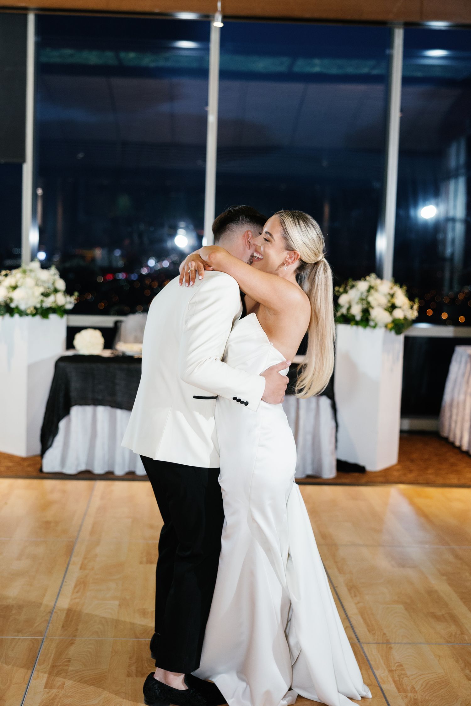 Bride and groom share first dance in elegant wedding reception venue at night.