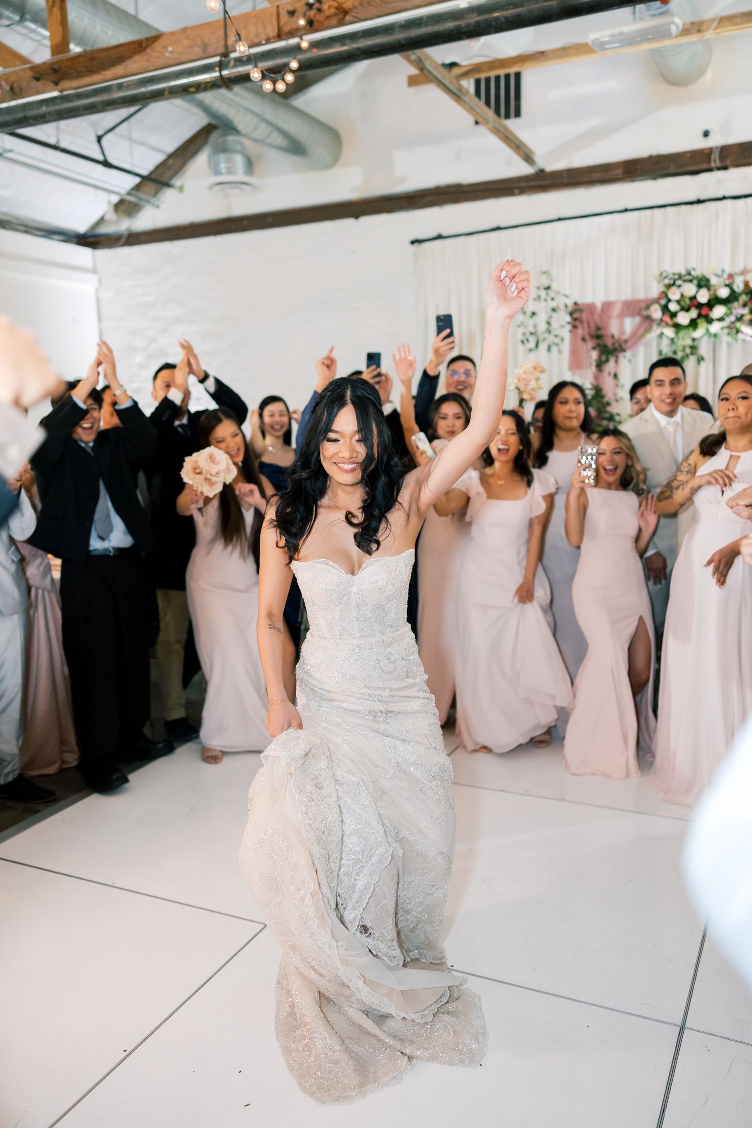 A celebration at a wedding reception with guests cheering in formal attire.