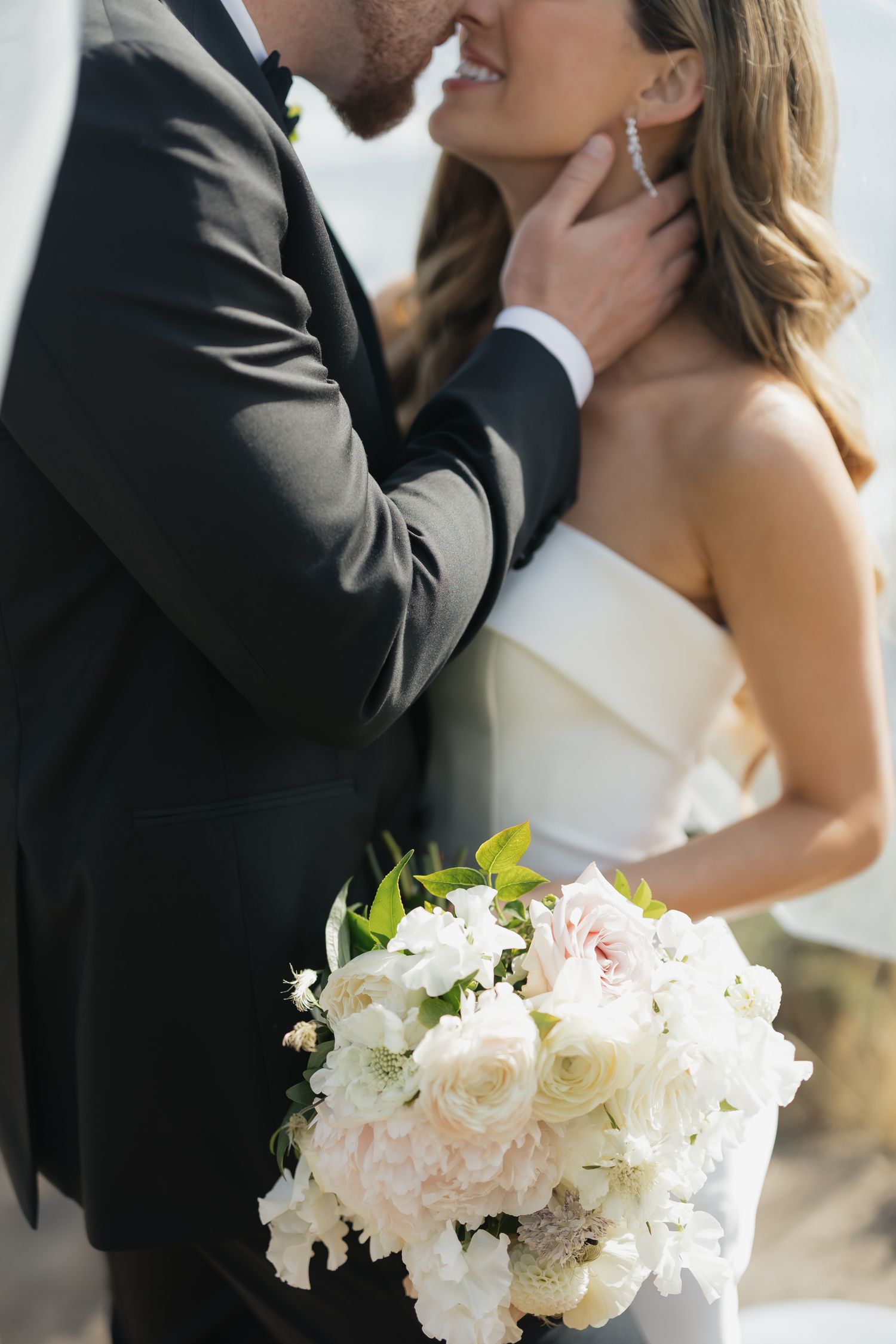 A romantic wedding moment with a beautiful white and blush pink bouquet in the foreground.