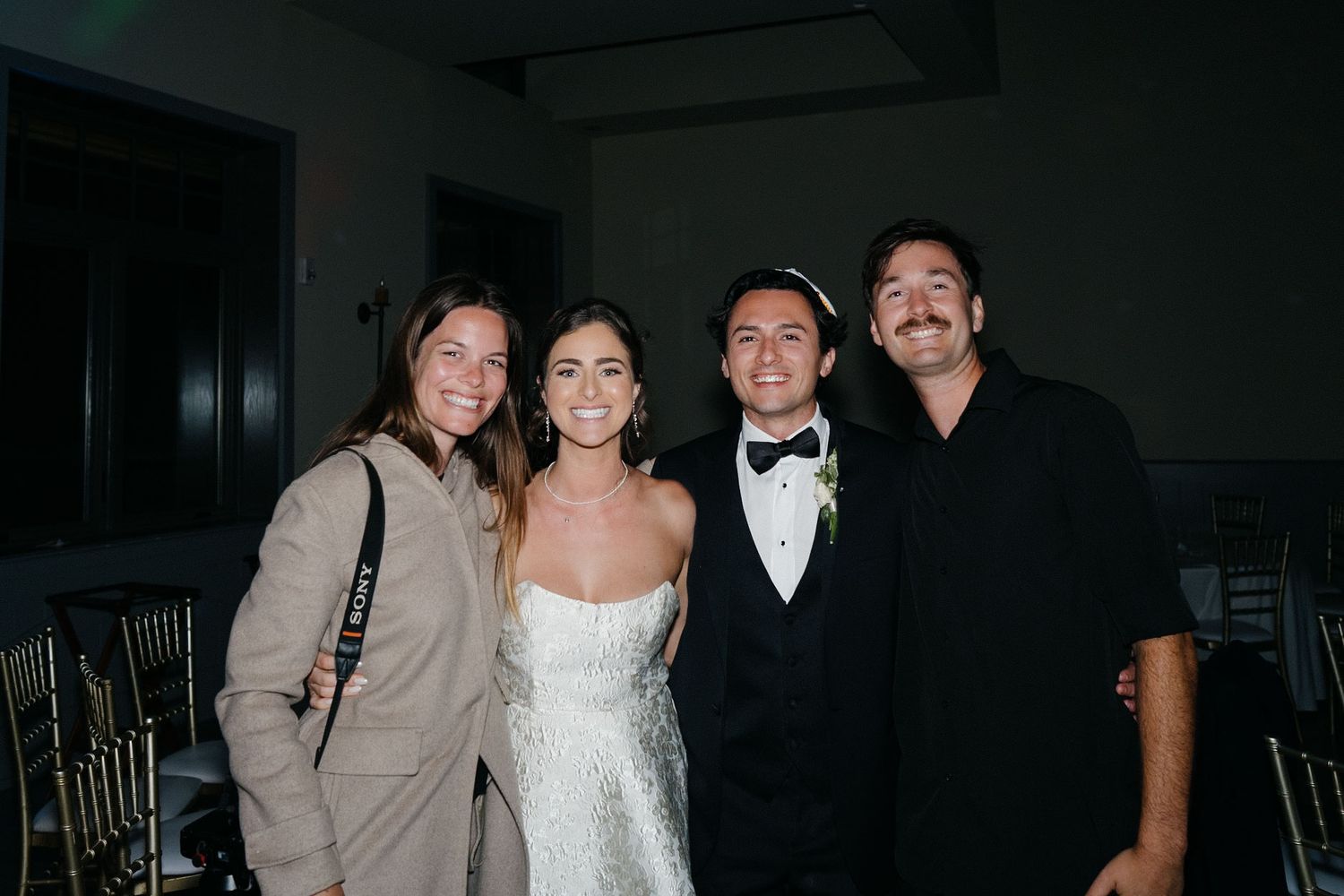 Wedding party members pose together during an evening reception celebration.