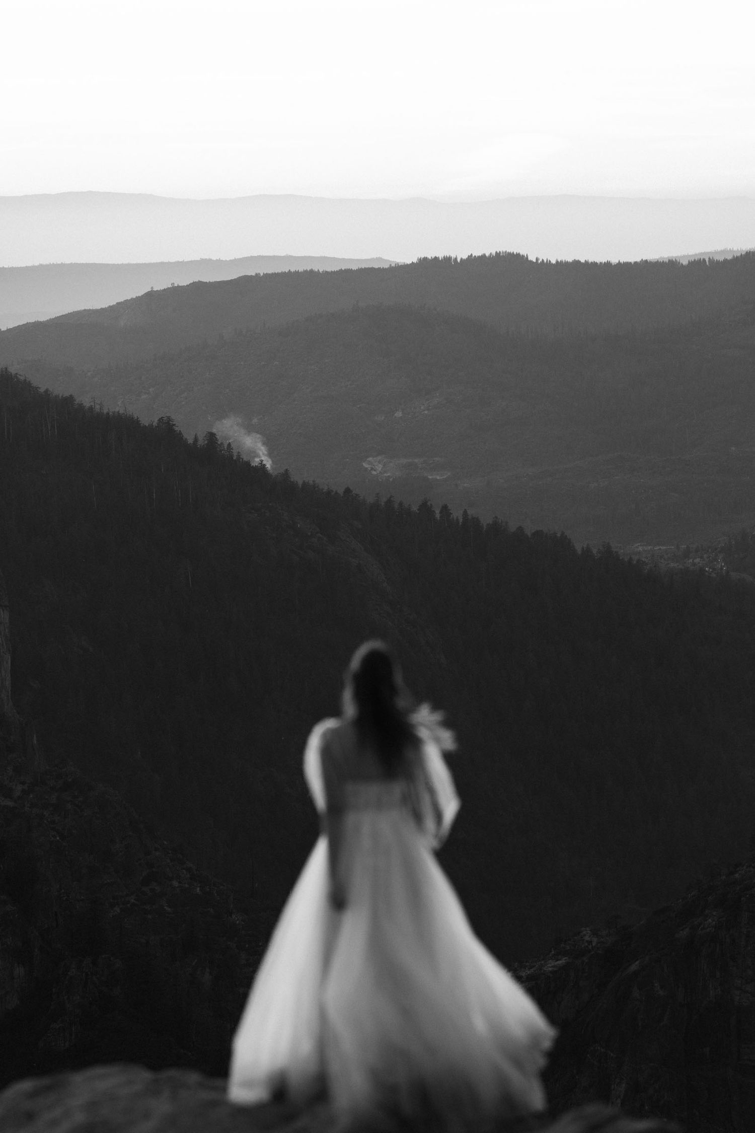 A bride in a white dress walks through the mountains at taft point in Yosemite national Park.