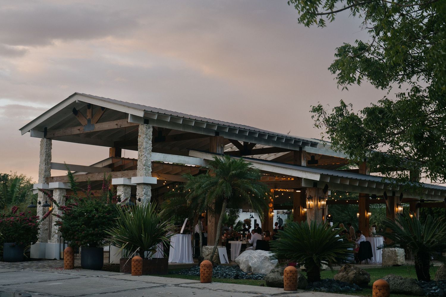 Modern gas station with illuminated canopy and convenience store at dusk with dramatic cloudy sky.