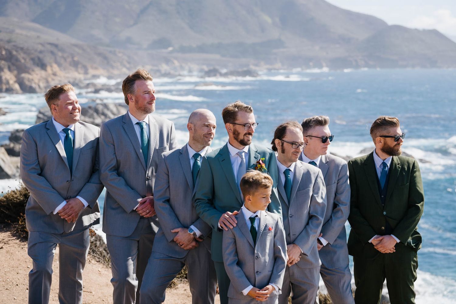 Dramatic coastal wedding photos on rocky cliffs overlooking the crashing waves of Big Sur, California.