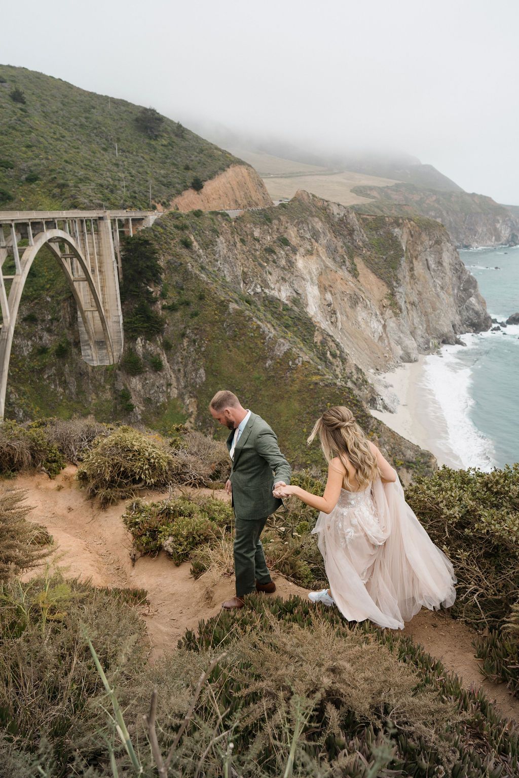 A romantic coastal photoshoot takes place along the cliffs of Big Sur with dramatic ocean views and rugged terrain.