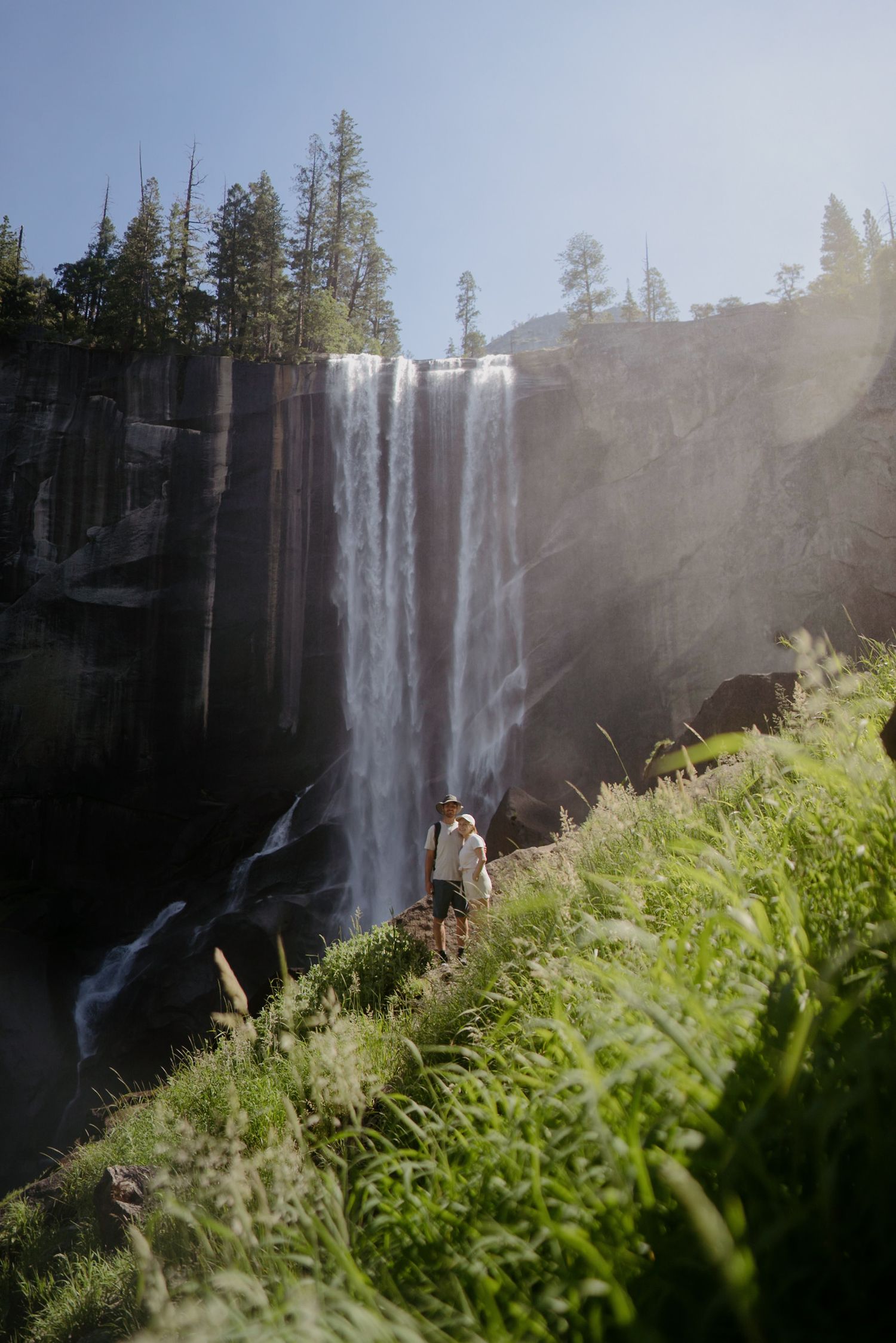 A cute couple posing in front of vernal falls in yosemite national park for their adventure session.