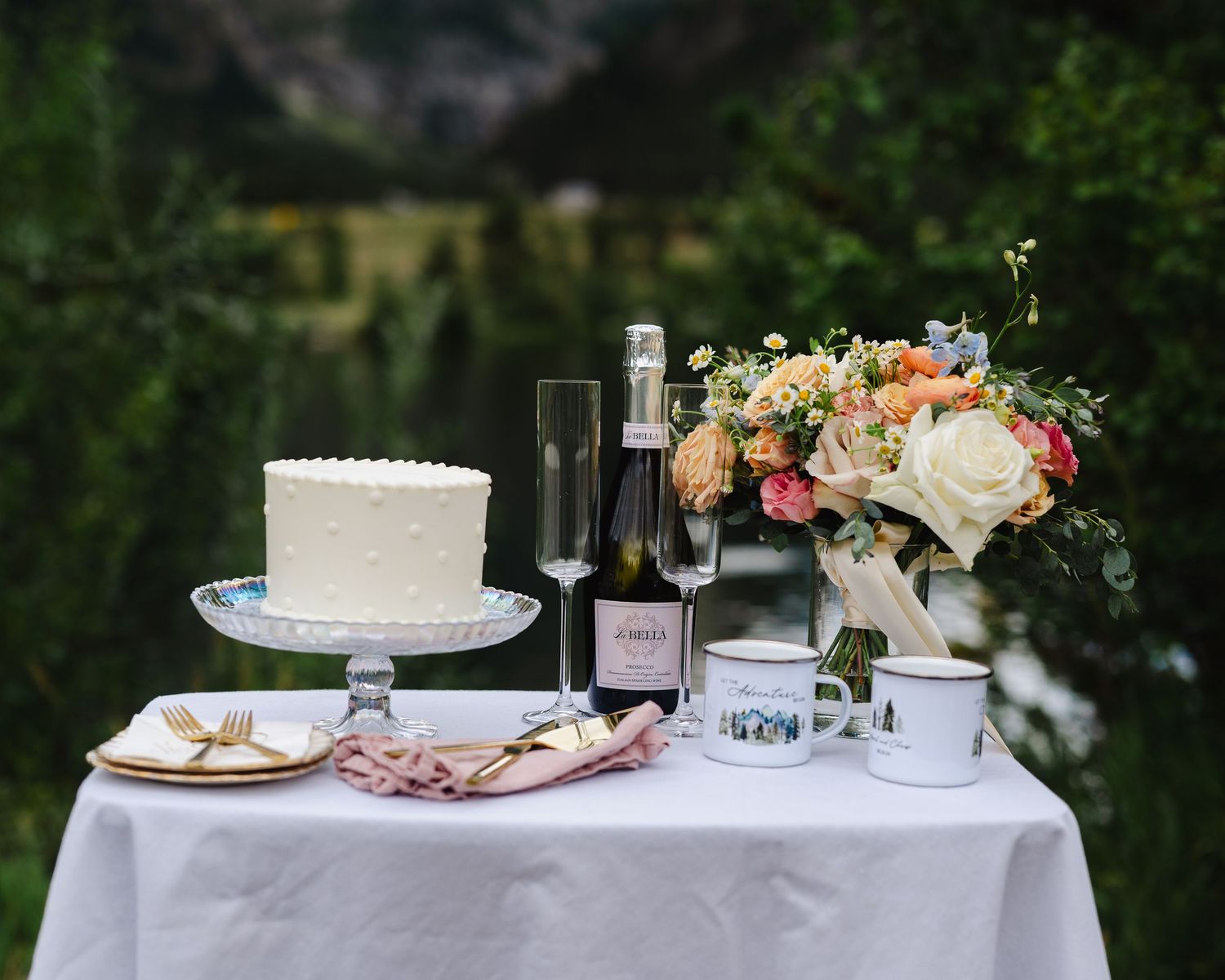 Elegant wedding reception table setup with white linens and floral centerpieces in an outdoor garden setting.