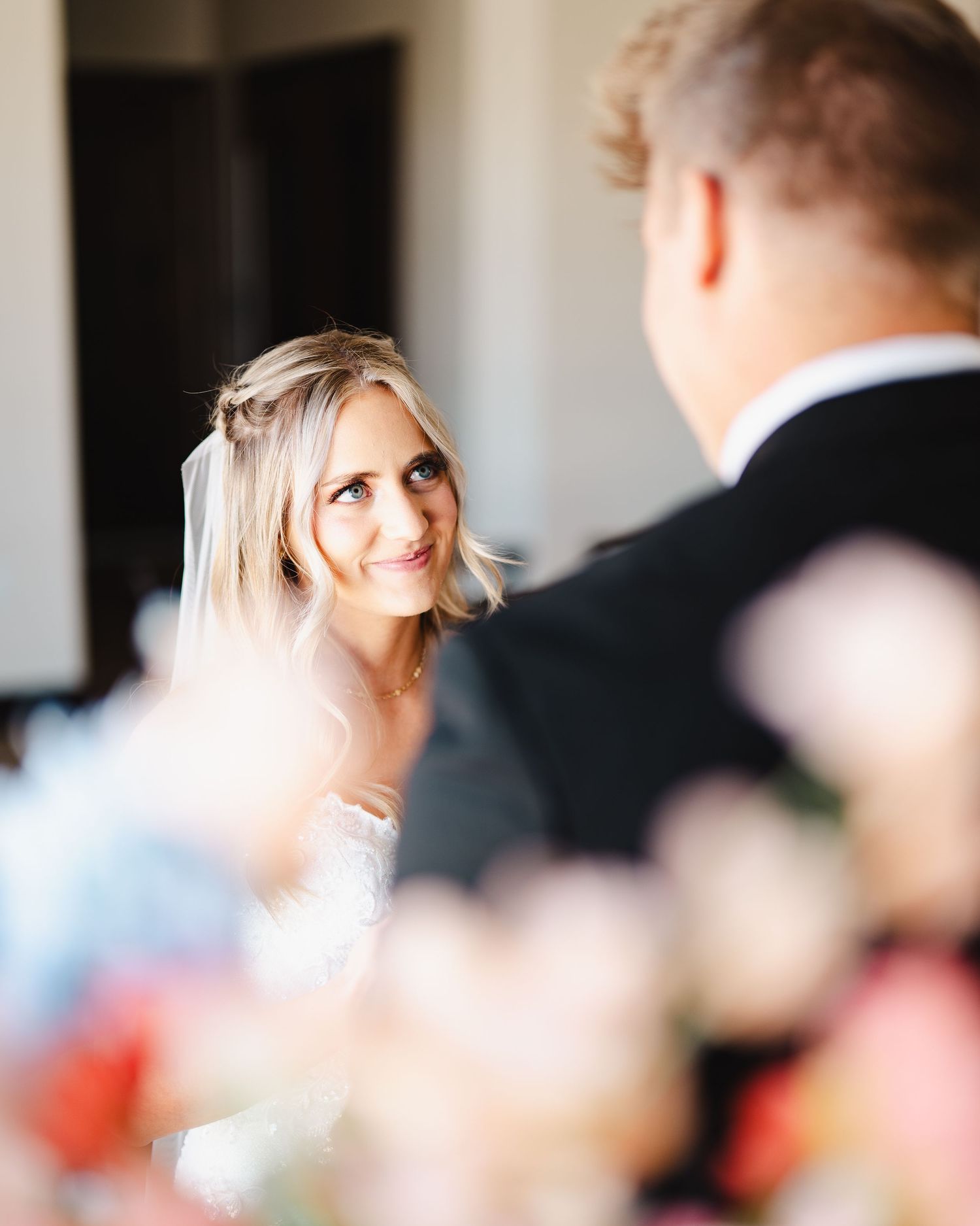 A romantic wedding moment captured in soft focus with delicate floral decorations in the foreground.