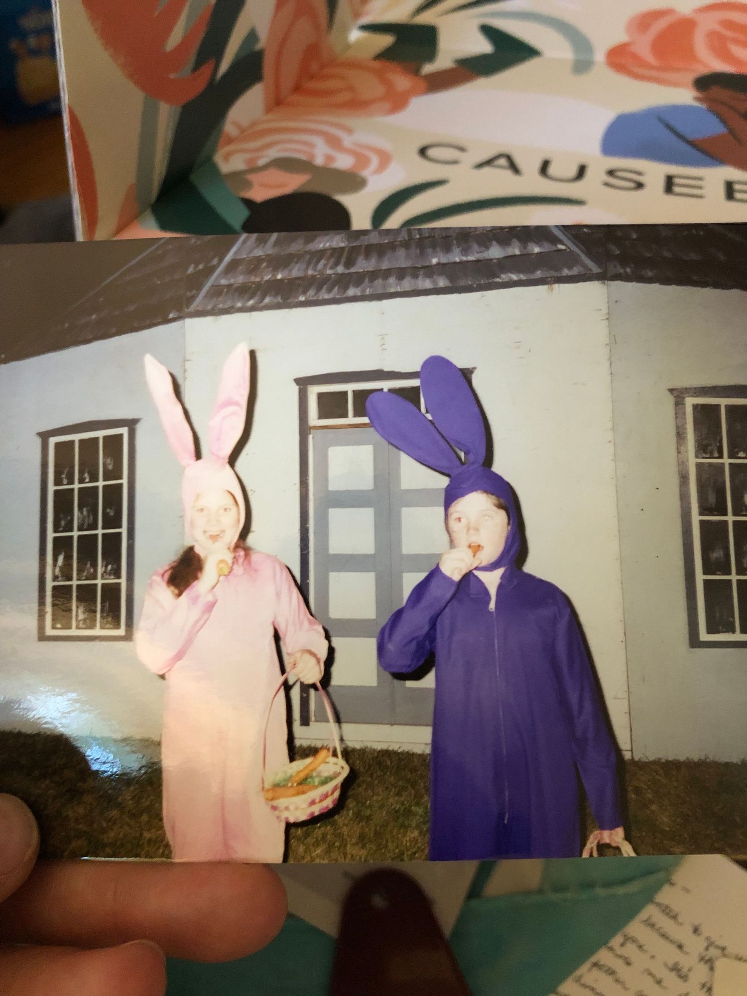 Two figures in pink and purple costumes stand outside a house at night.
