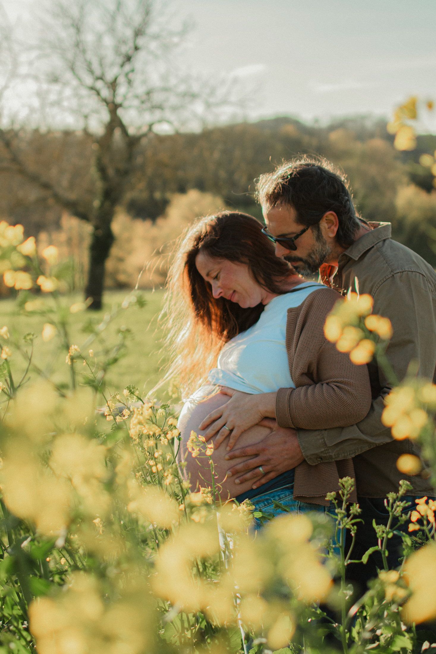 Couple attendant un enfant dans un champ de colza