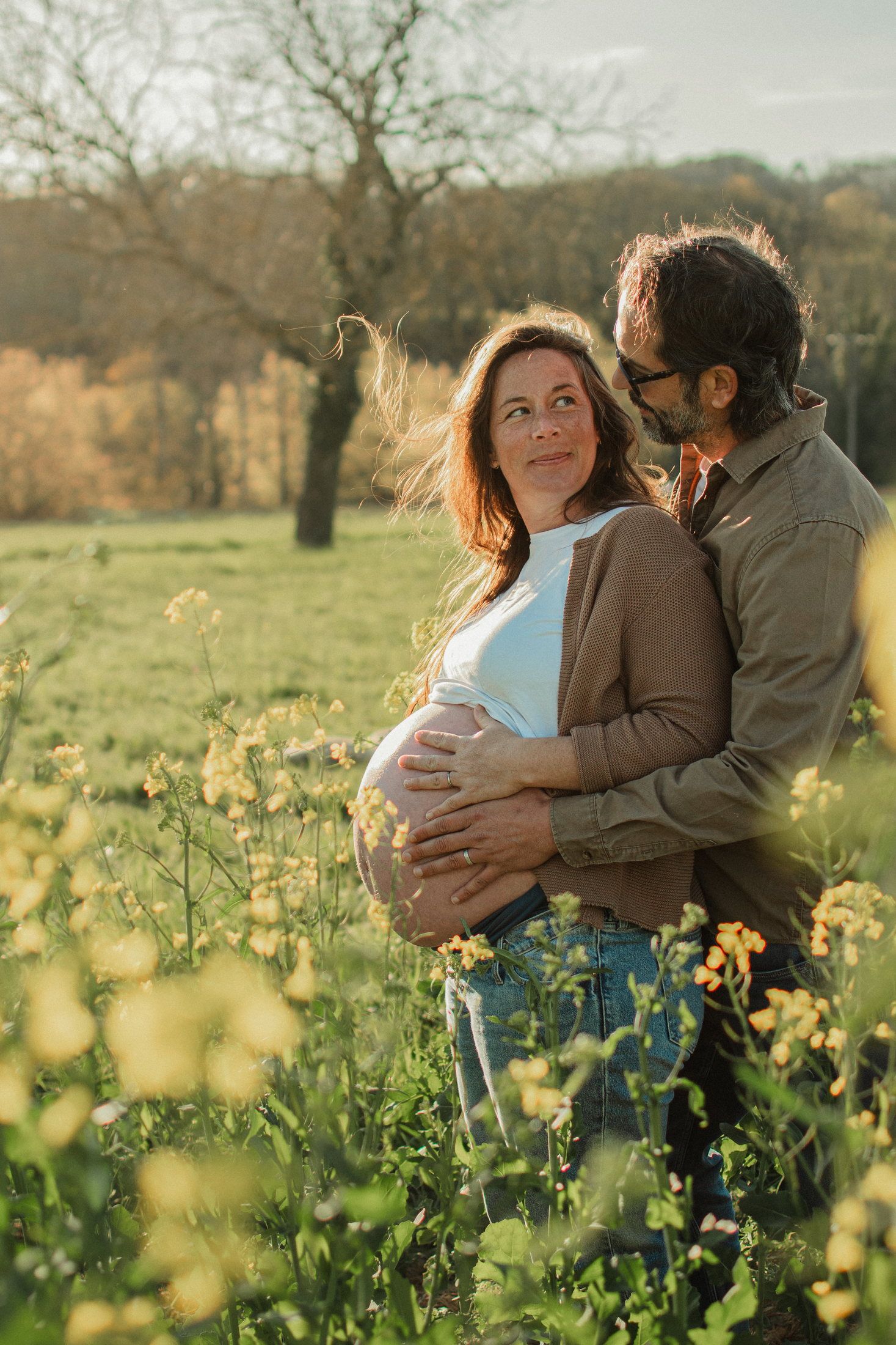 Couple attendant un enfant dans un champ de colza
