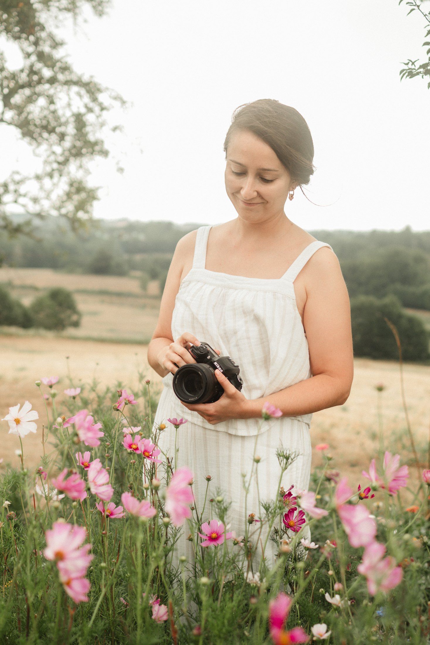 Marjorie, photographe de mariage et de famille, tenant son appareil au milieu des fleurs