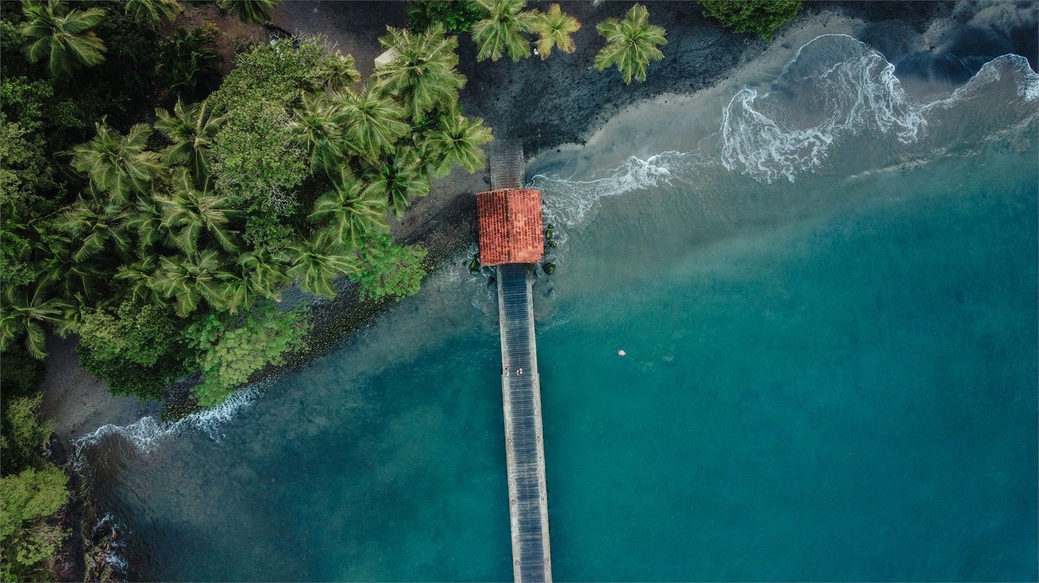 Ponton surplombant une baie aux eaux turquoise vue du ciel
