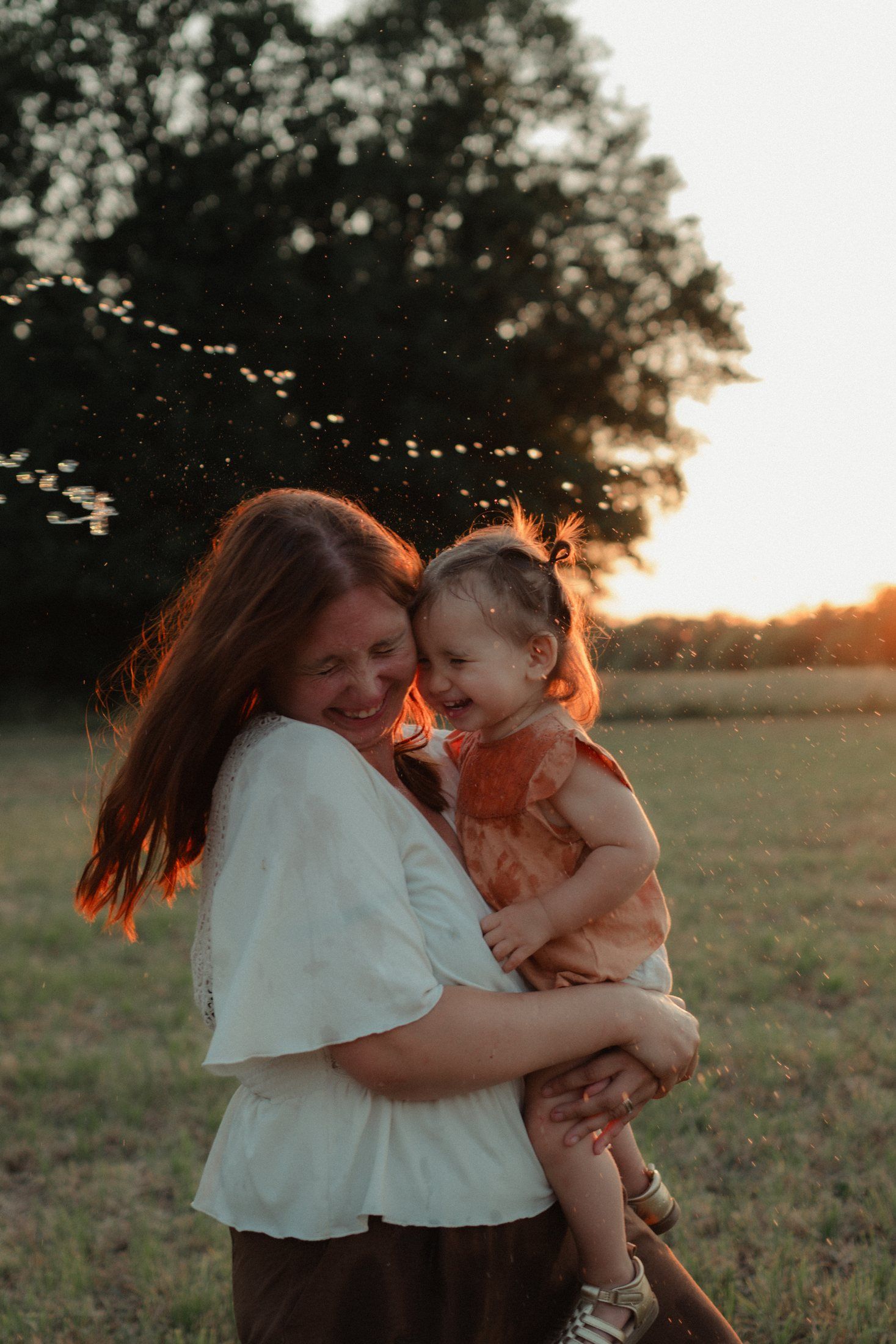 Mère serrant sa fille dans ses bras au coucher du soleil