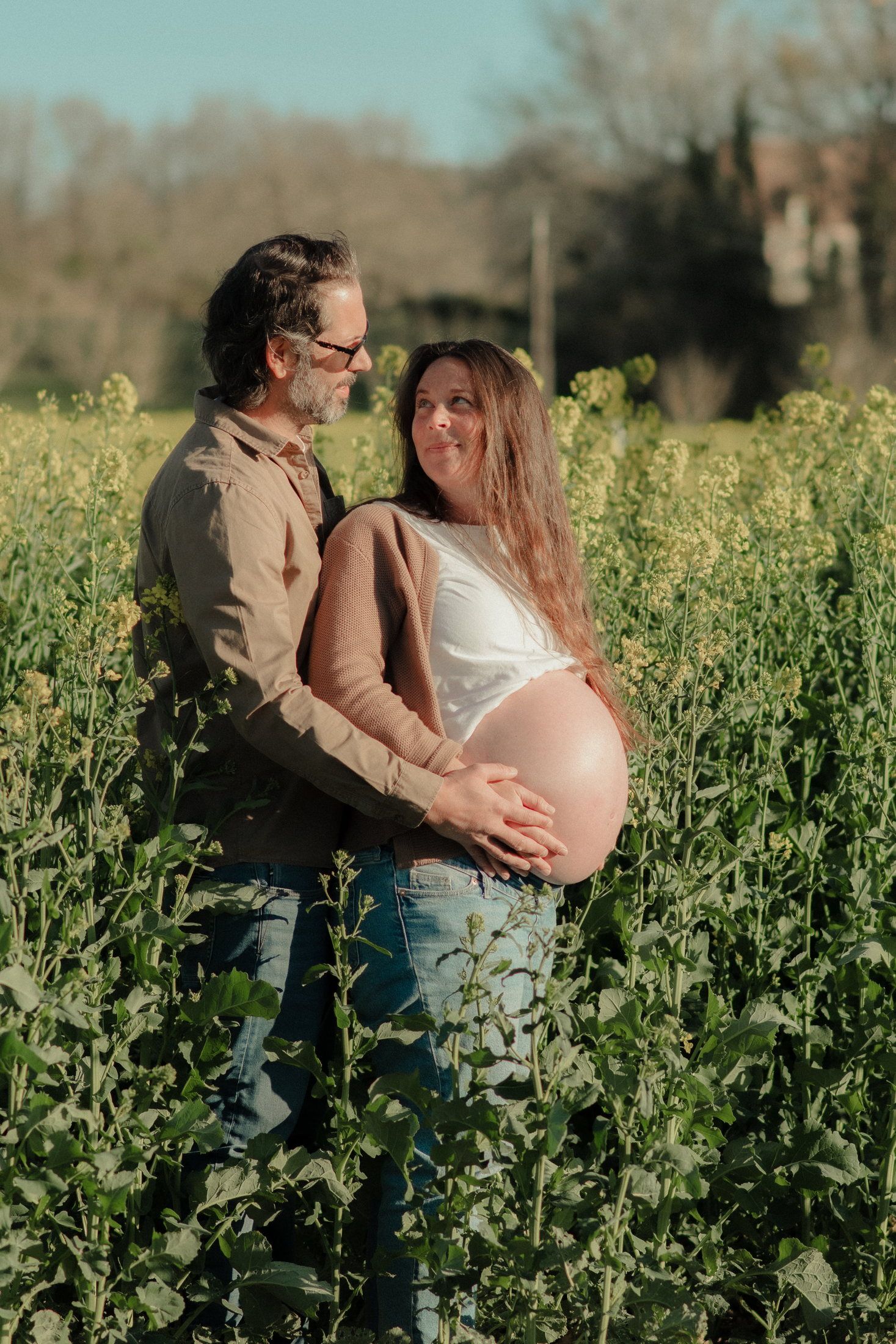 Couple attendant un enfant dans un champ de colza
